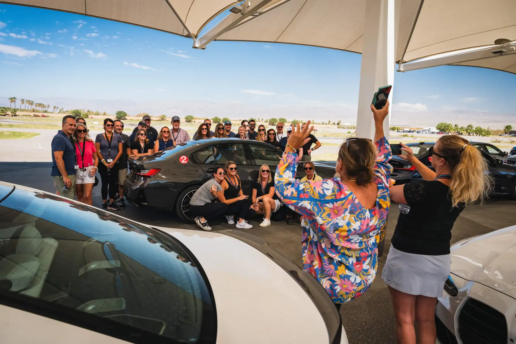Group posing for a photo behind a BMW under the paddock canopy