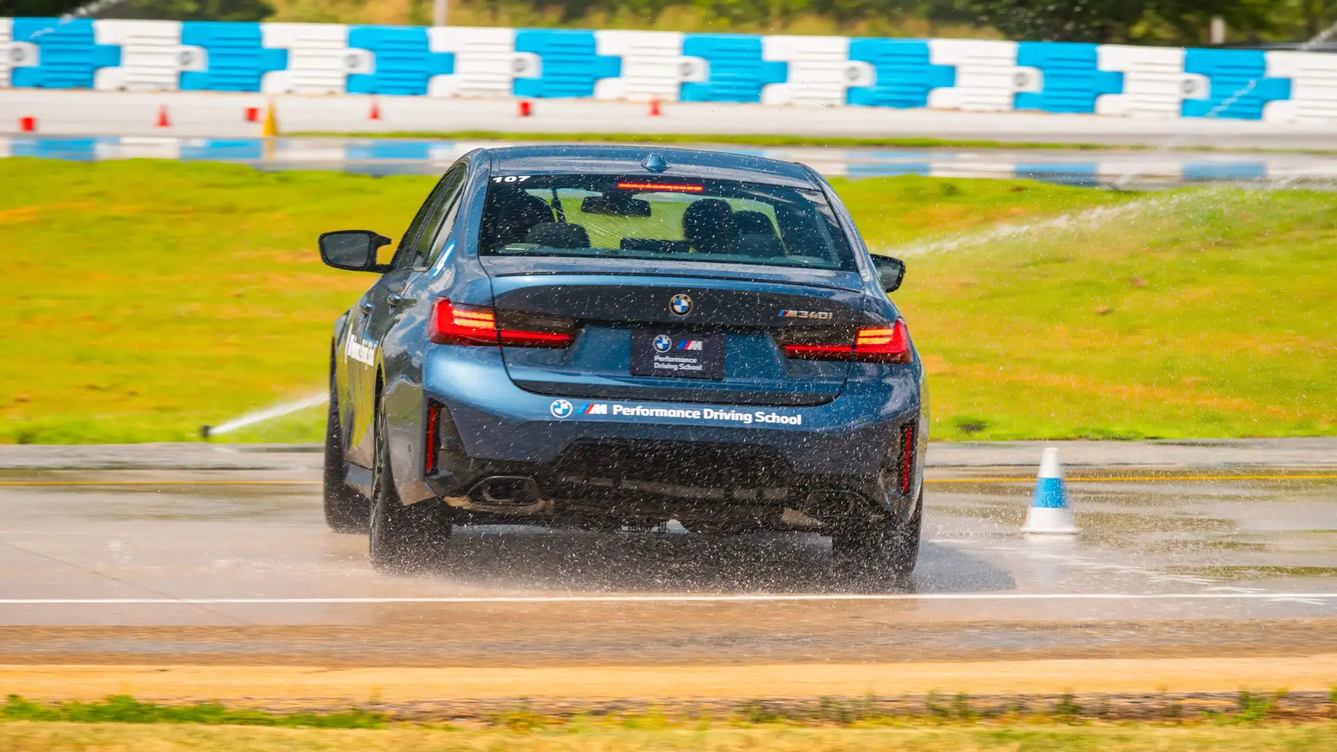BMW M340i braking hard on the wet skid pad, throwing up spray