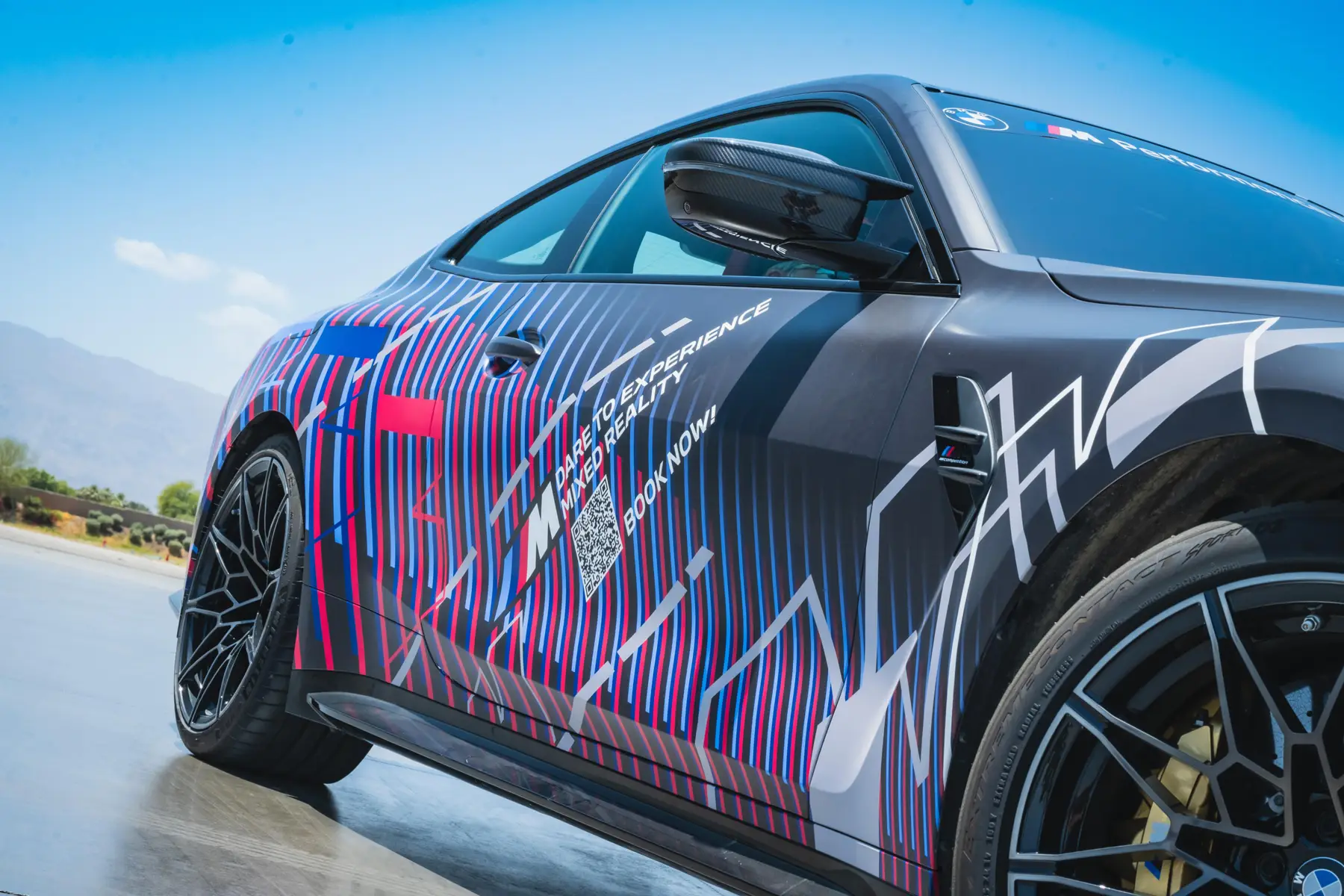 Close-up of the mixed-reality BMW M4's graphic wrap reading 'Dare to experience mixed reality'