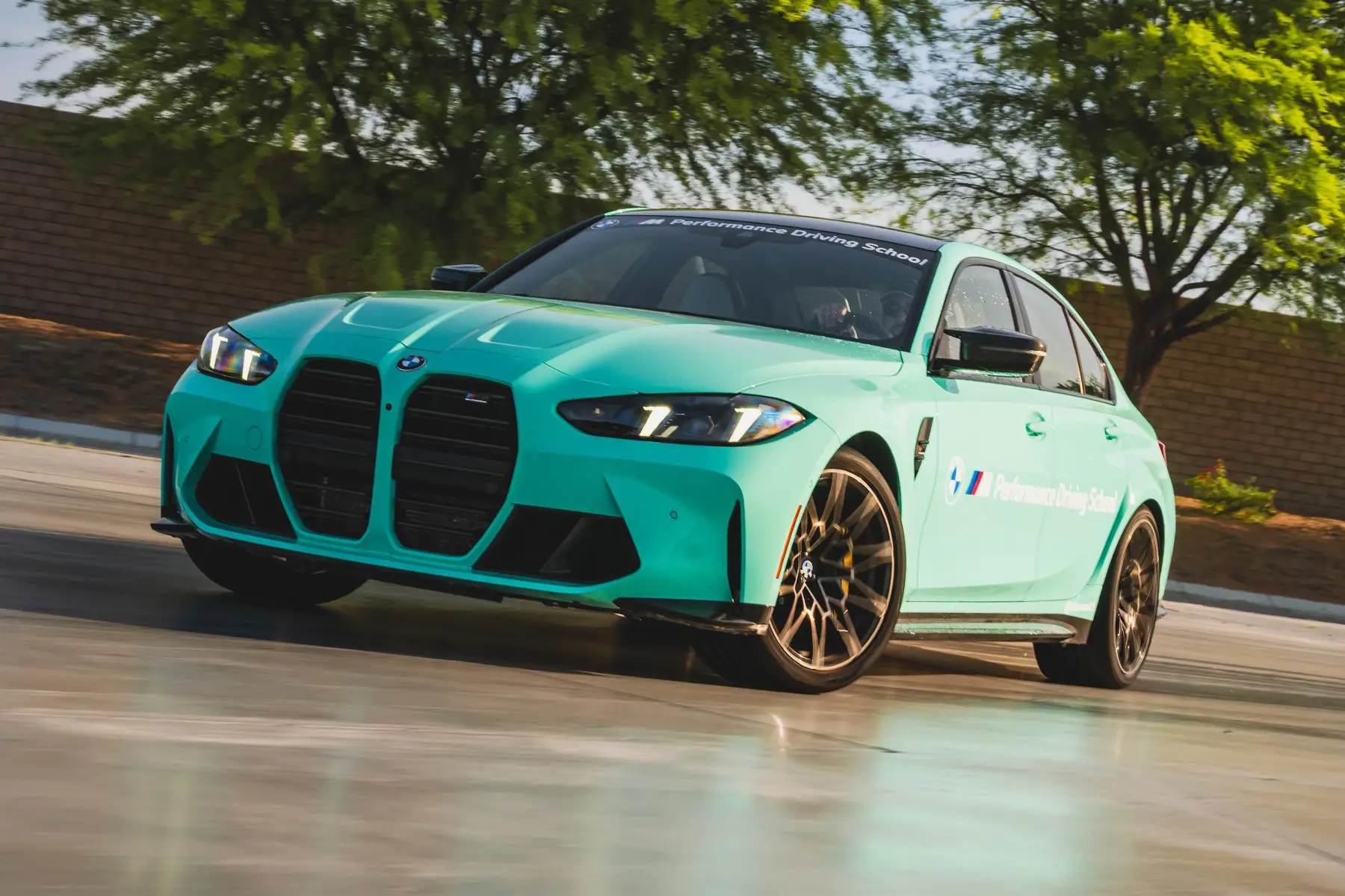 Mint green BMW M3 sliding across the wet pad