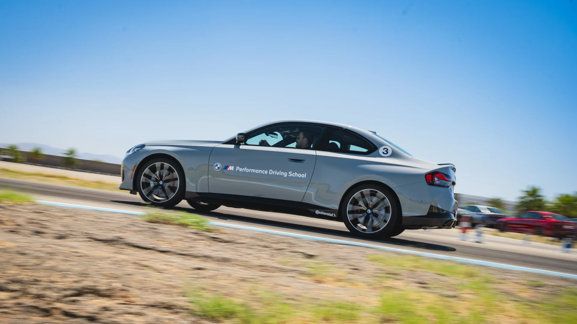 Silver BMW M2 at speed on the desert circuit