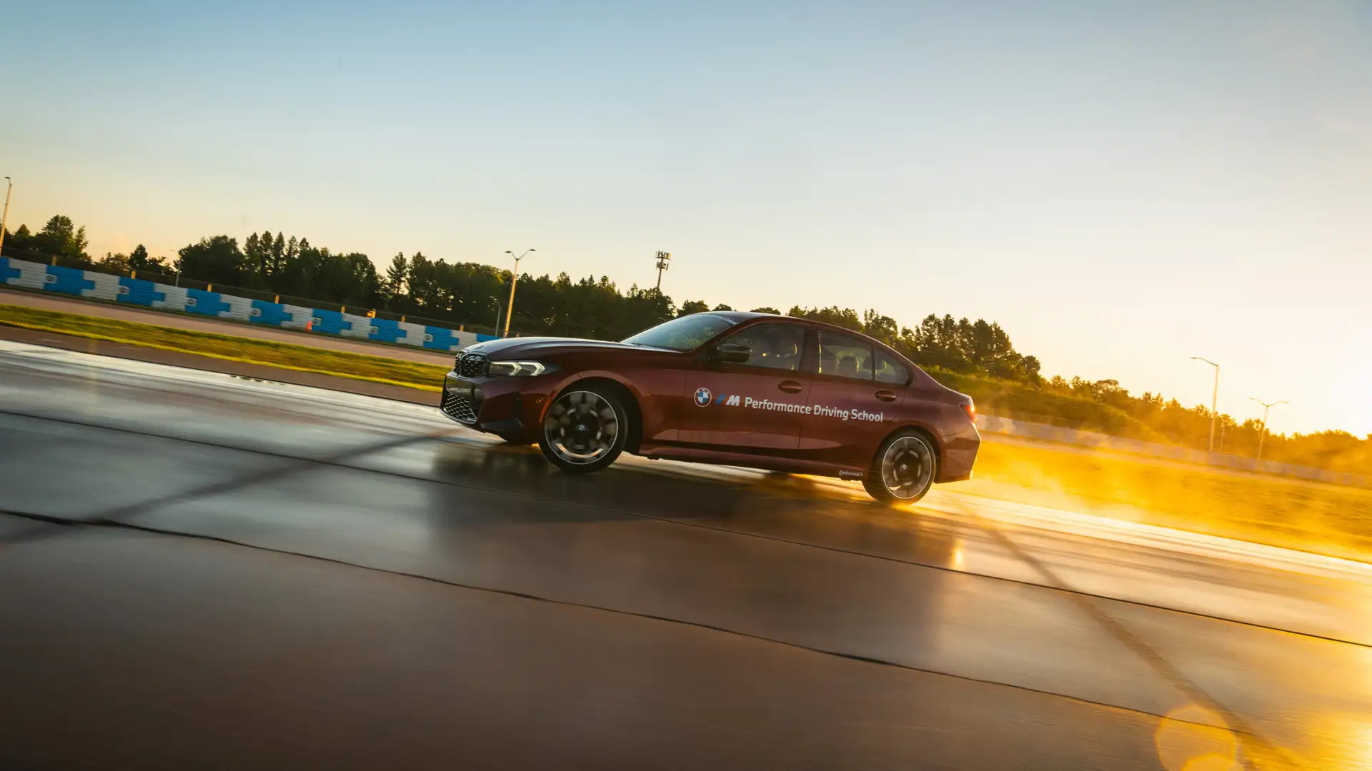 Dark red BMW M3 at speed on the circuit at sunset