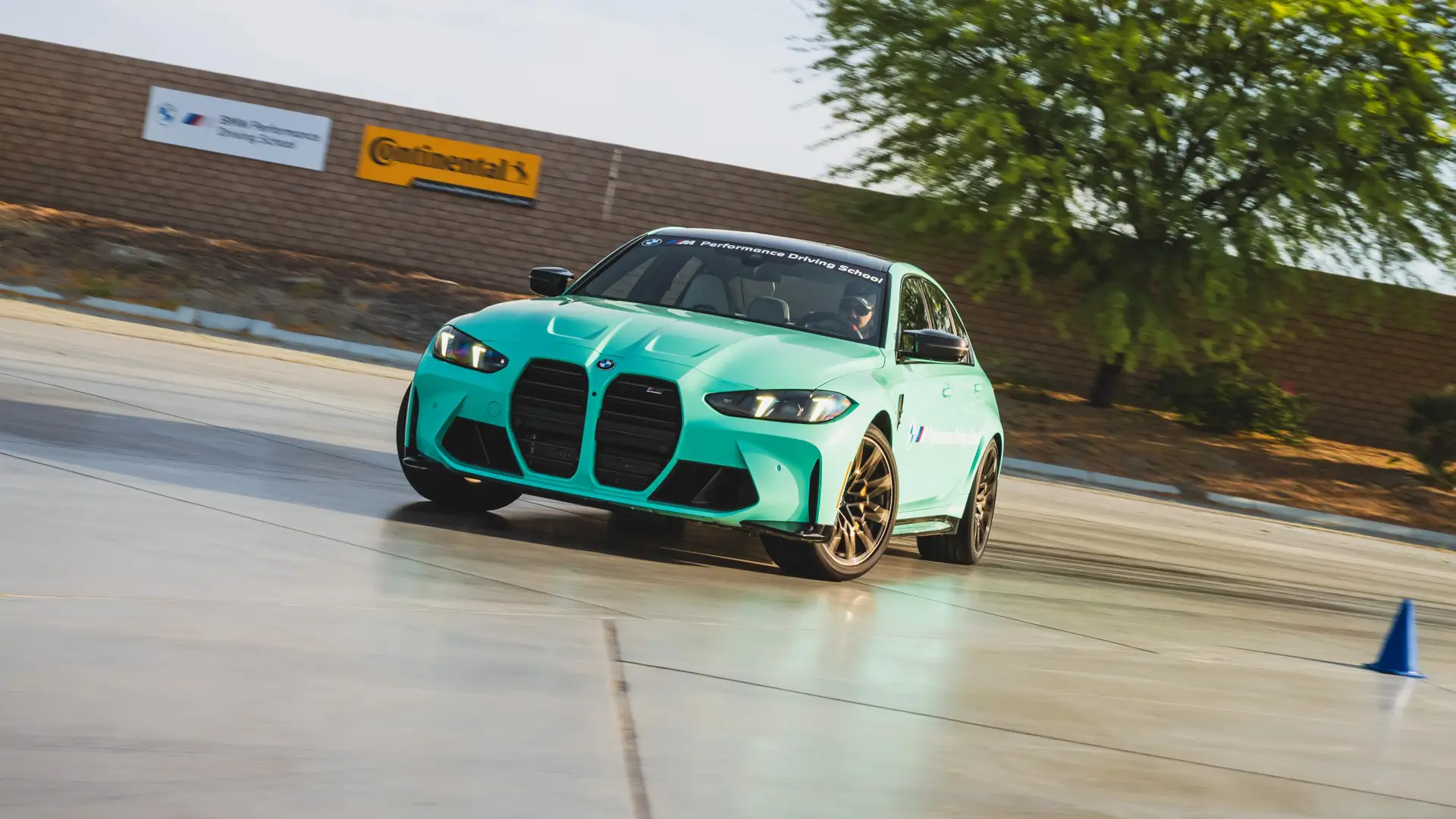 Mint green BMW M3 sliding on the wet pad past a Continental banner