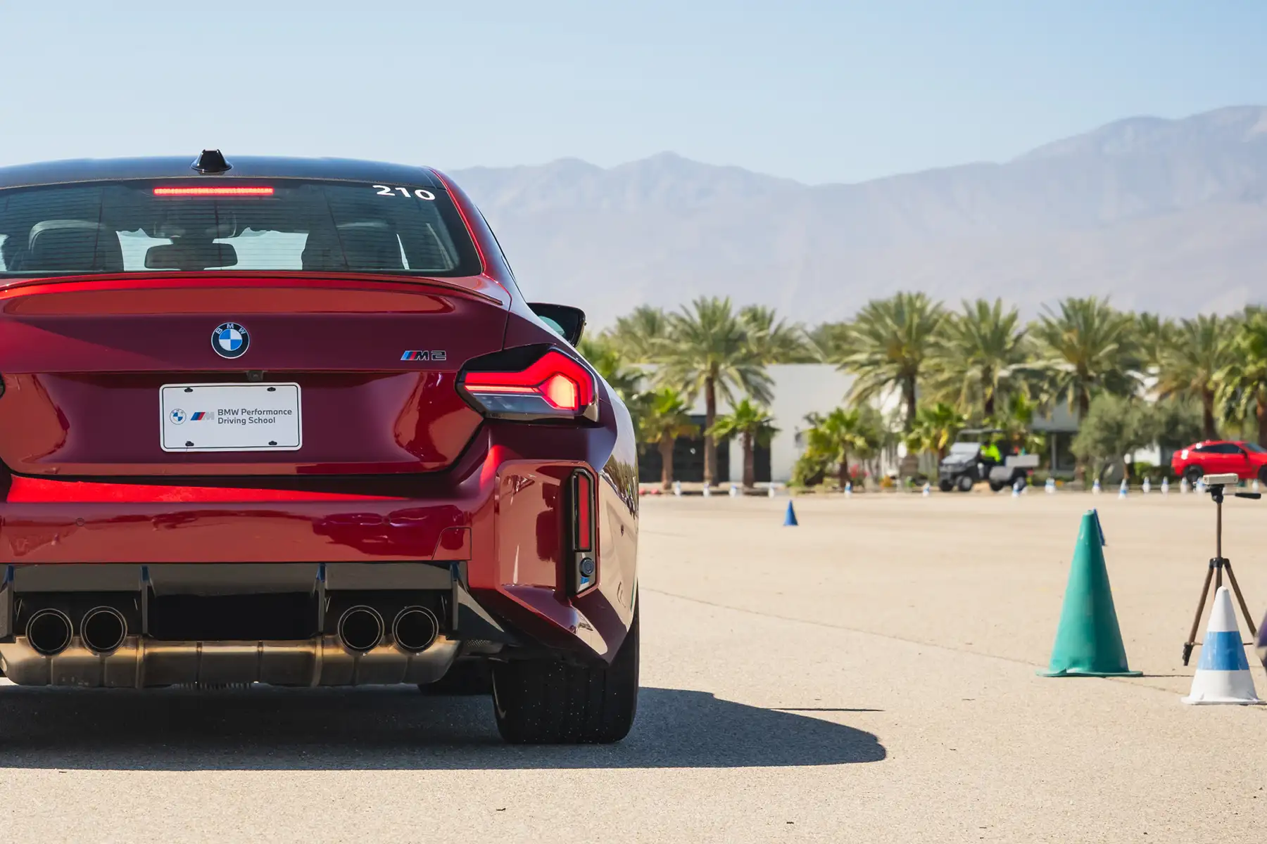 Red BMW M2 waiting at the start line beside a timing cone
