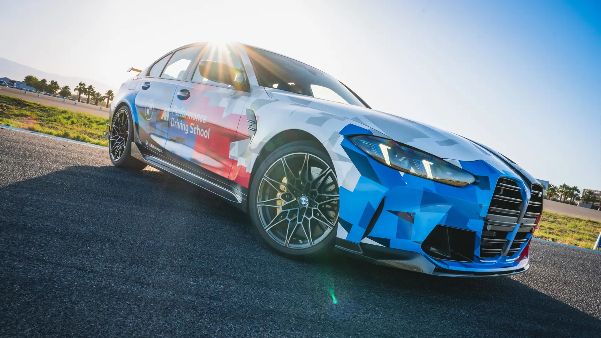 BMW M3 in Motorsport livery parked on the apron with the sun behind it