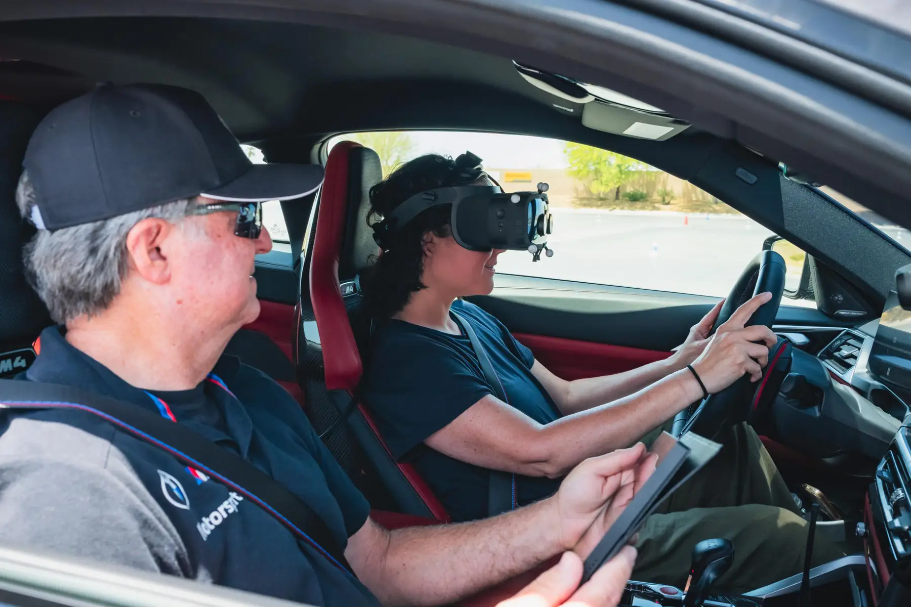 Instructor with a tablet beside a driver wearing a mixed-reality headset