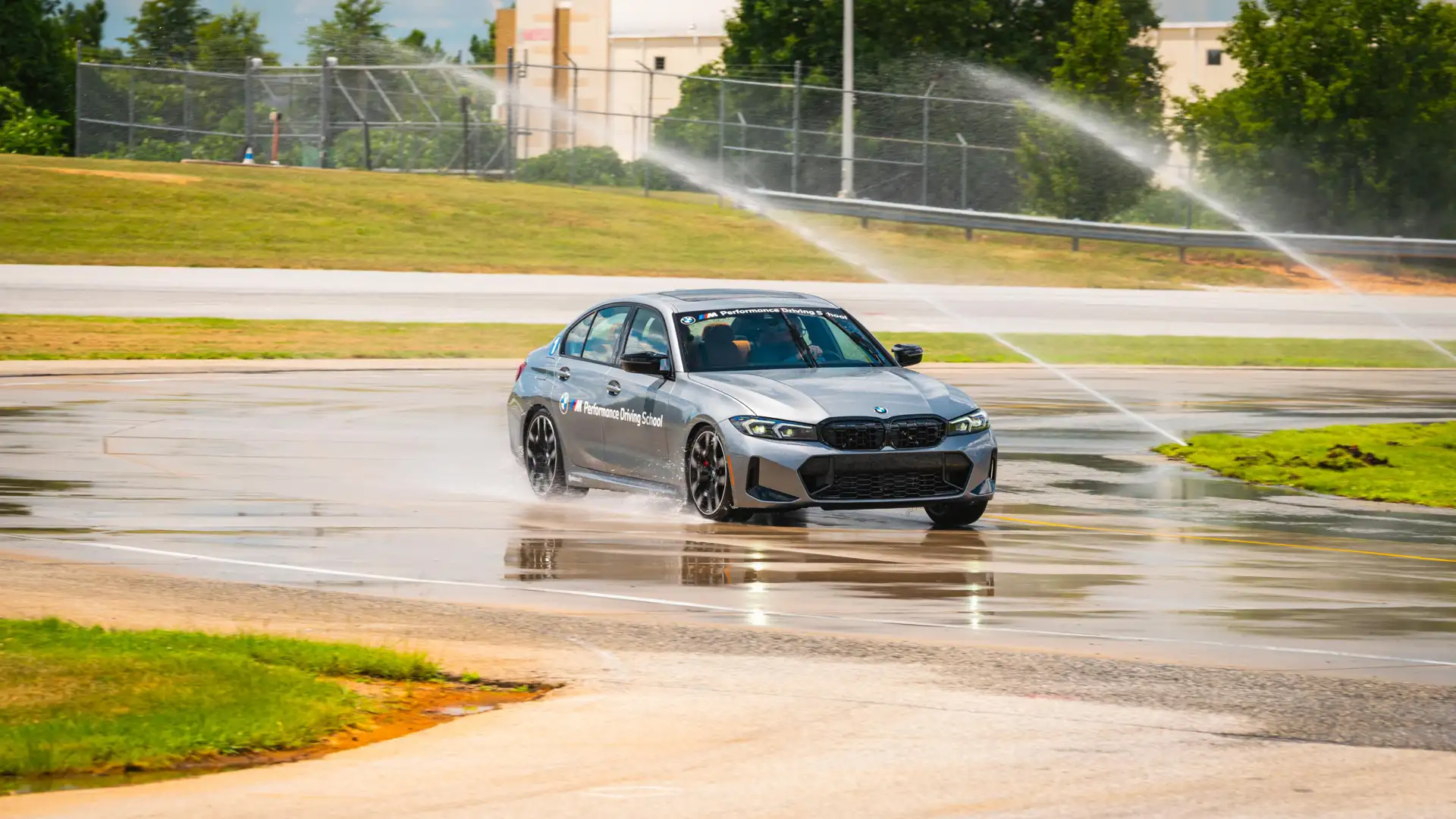Grey BMW M340i sliding through water on the wet skid pad
