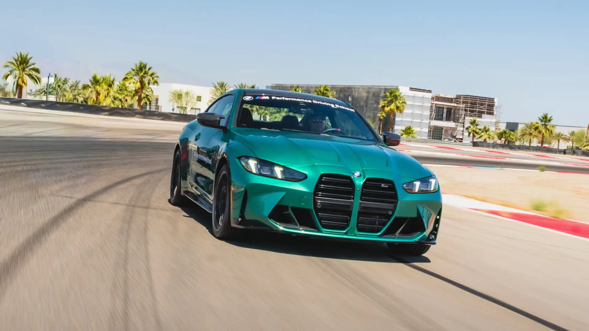 Green BMW M4 at speed on the desert circuit