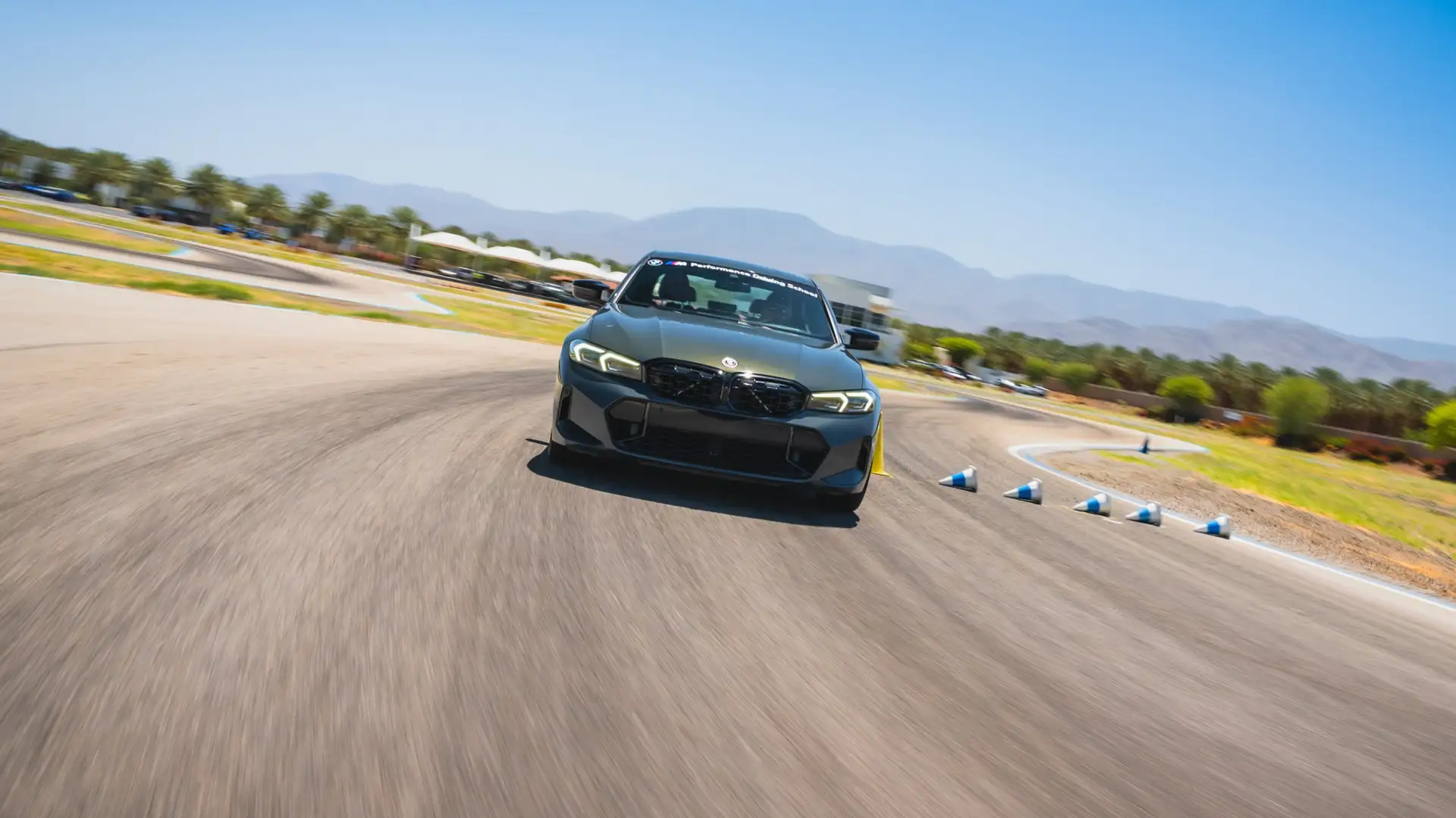 Grey BMW M340i at speed past a line of cones on the circuit