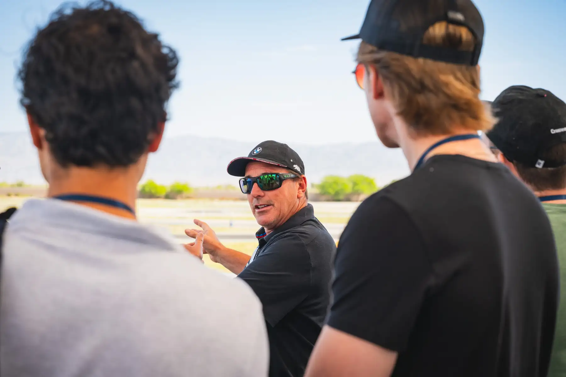 Instructor gesturing as he briefs a group of students trackside