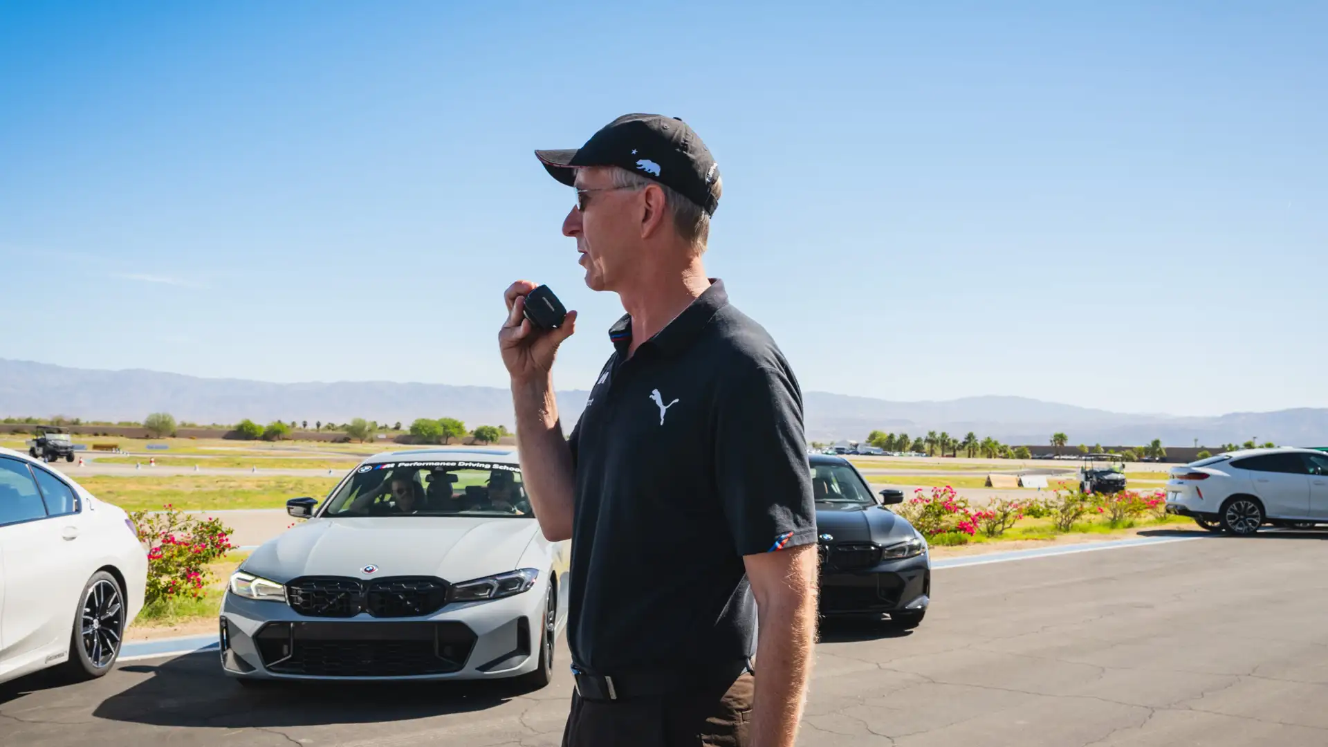 Instructor speaking into a handheld radio beside the school cars