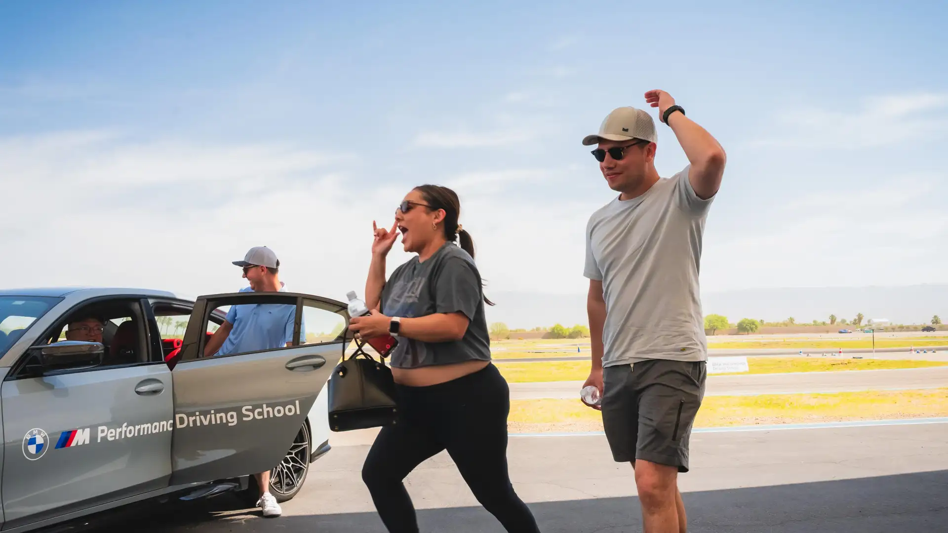 Two guests walking away from a BMW Performance Driving School car, laughing