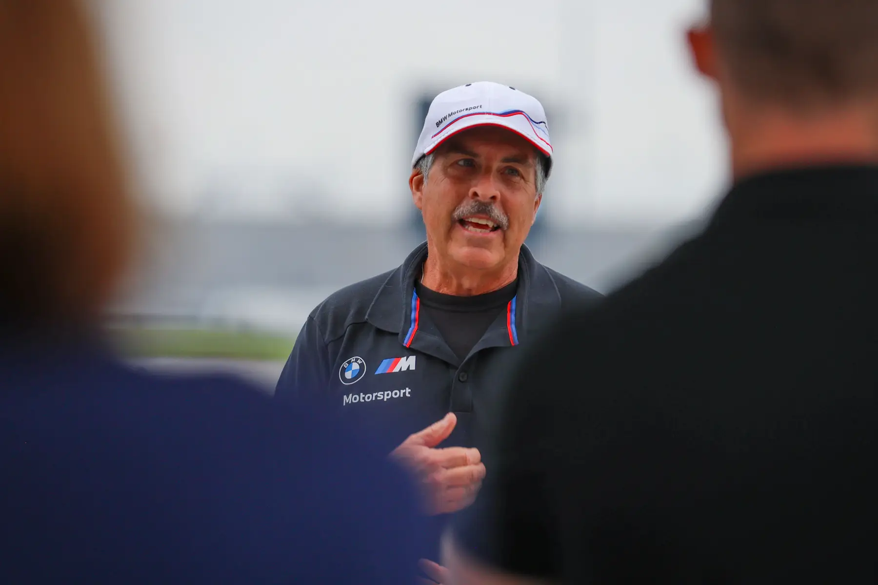 Instructor in a BMW Motorsport cap talking with participants