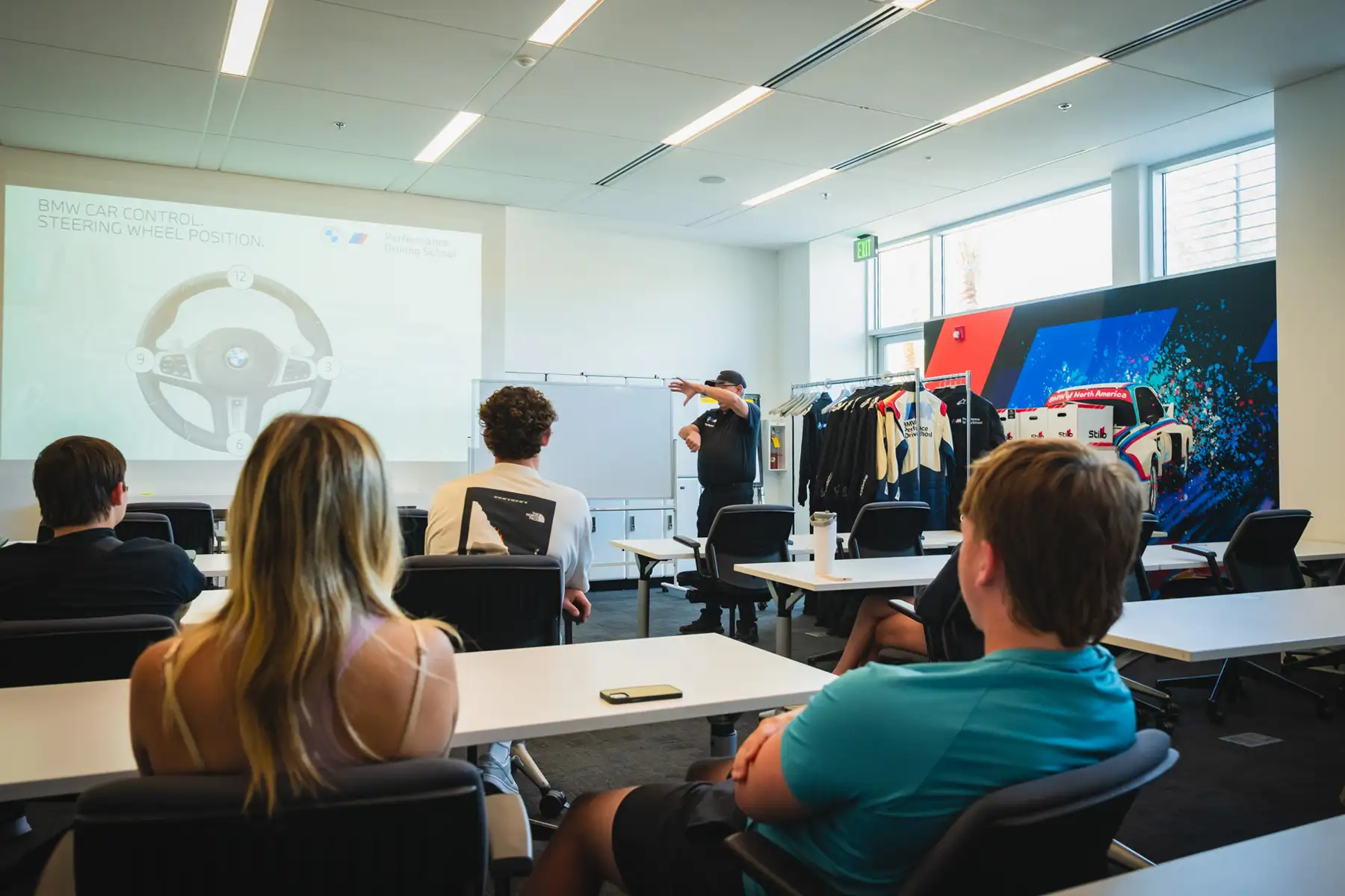 Instructor presenting a steering-wheel position slide to teenage students