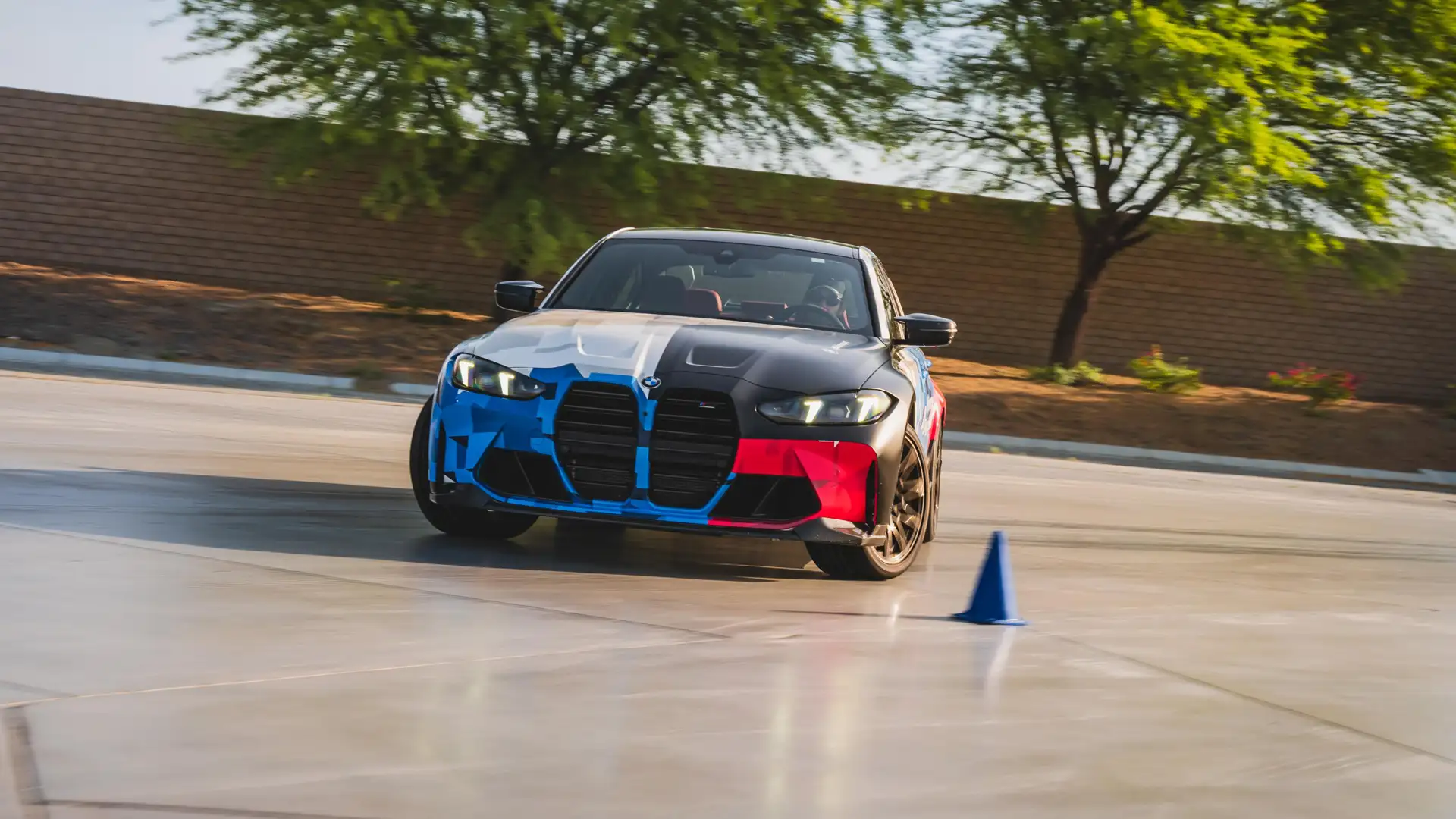 BMW M3 in Motorsport livery on the wet pad beside a cone