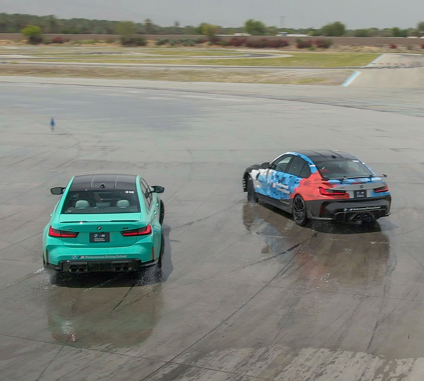Mint green BMW M3 and a liveried M2 on the wet skid pad, seen from above