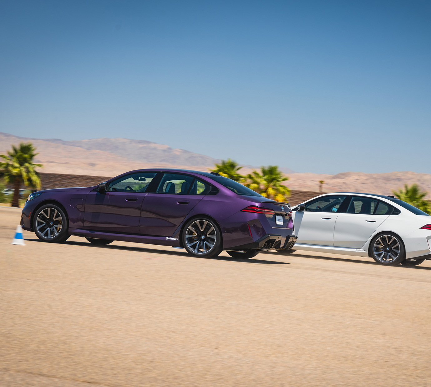 Purple BMW M5 following a white M5 across the apron