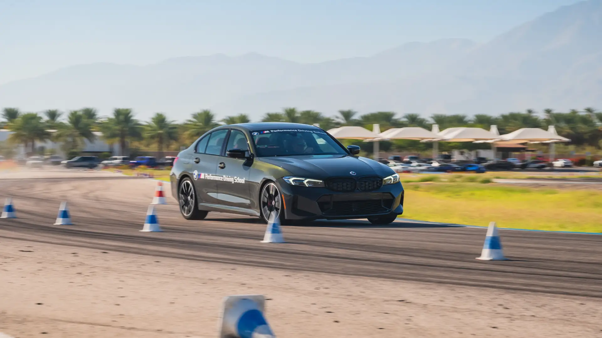 Dark BMW M340i threading a line of blue cones on the desert circuit
