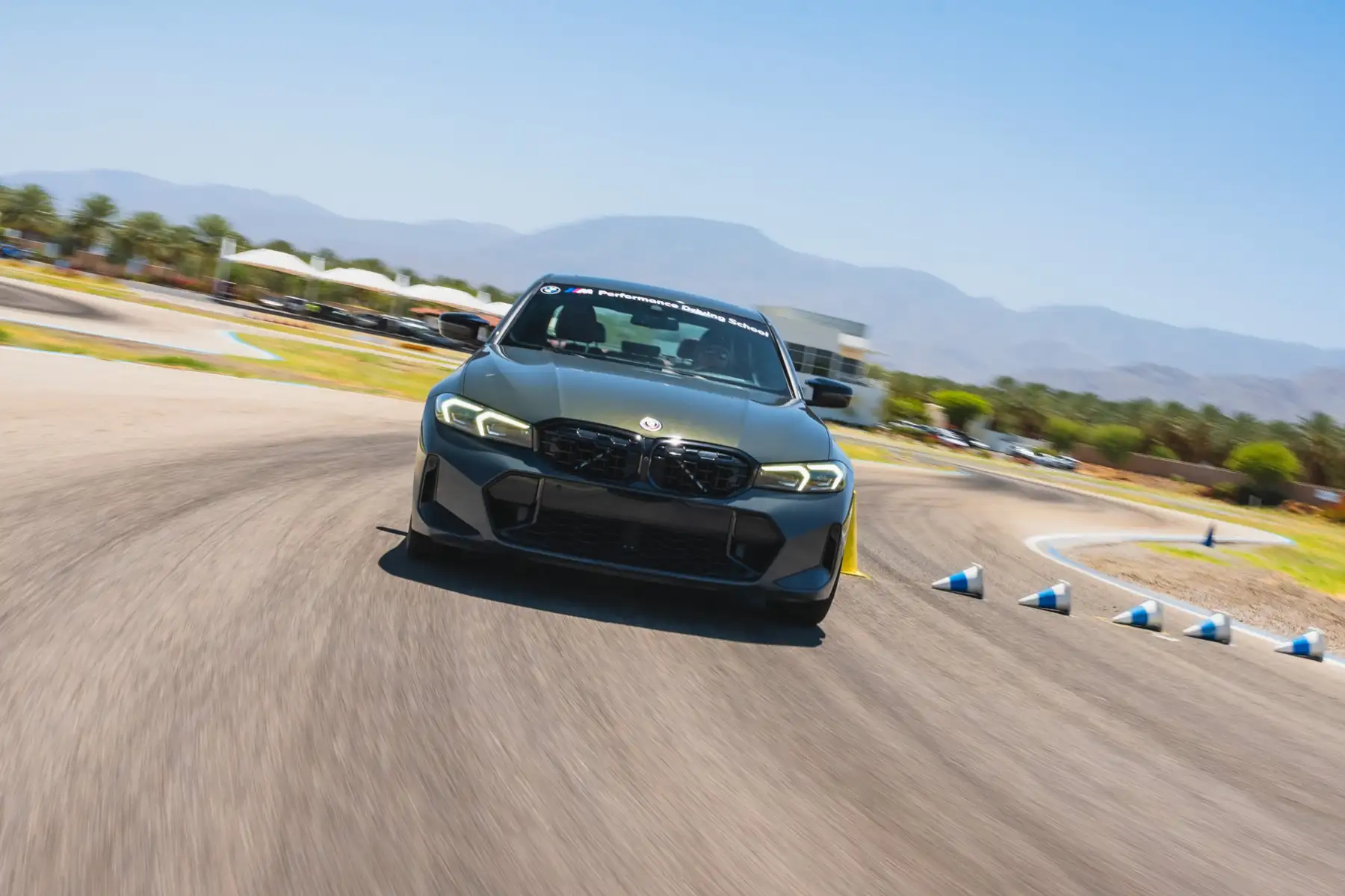 Grey BMW M340i at speed towards a line of cones