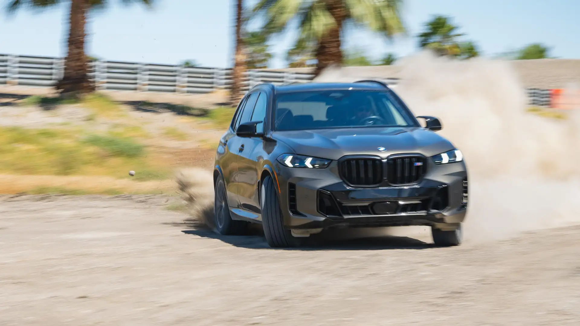 Dark BMW X5 sliding through gravel, throwing up dust