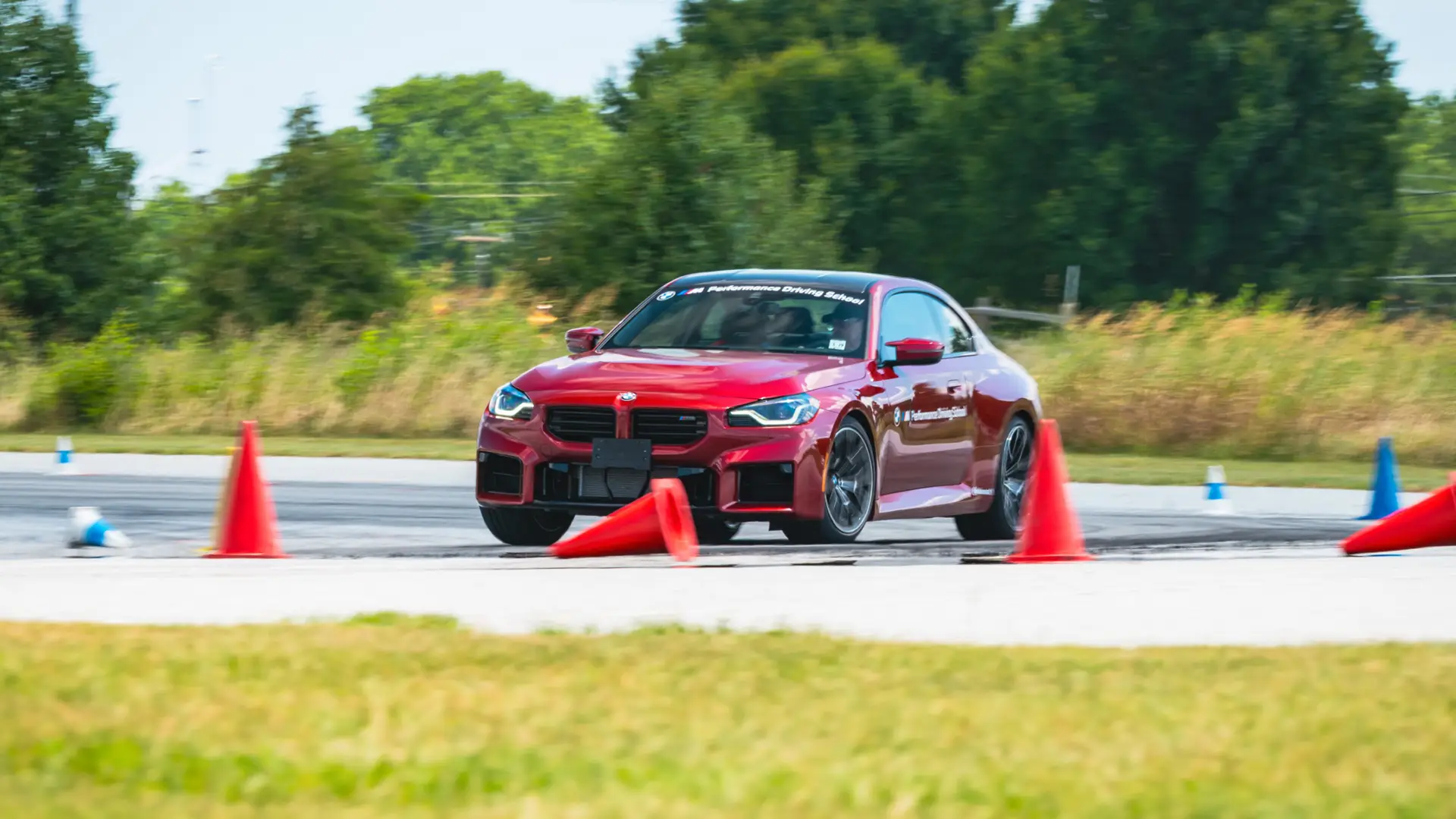 Dark red BMW M2 threading a line of orange cones