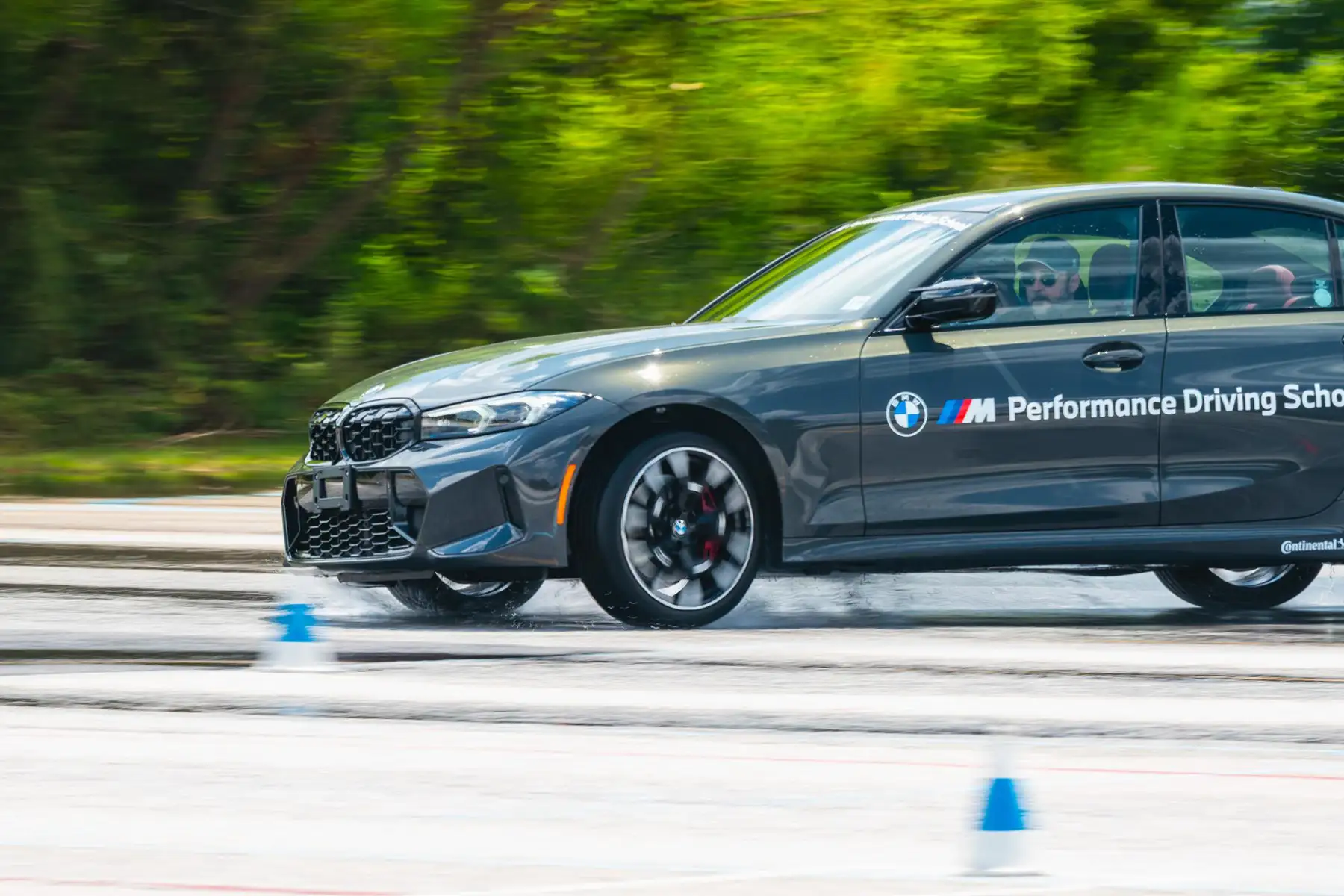 Grey BMW M340i sliding across the wet skid pad