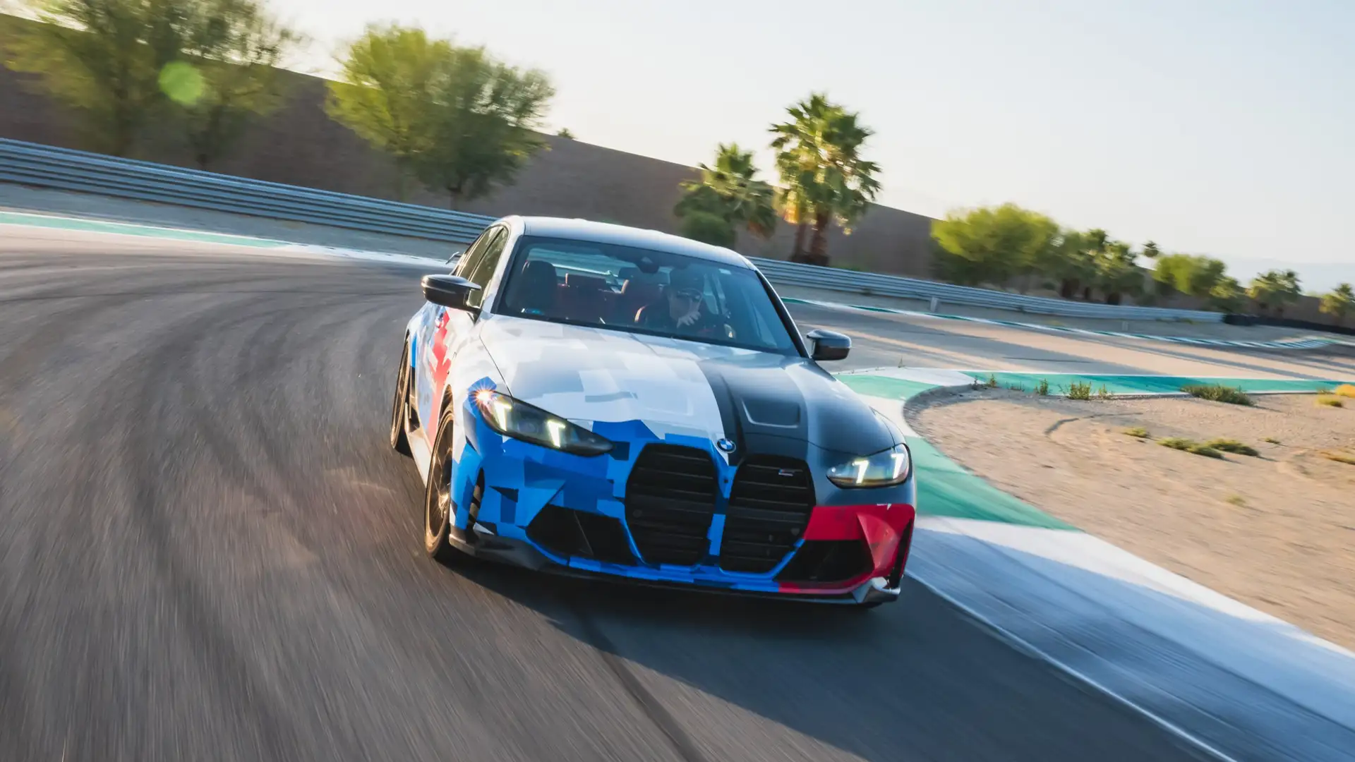 BMW M3 in Motorsport livery cornering on the desert circuit at dusk