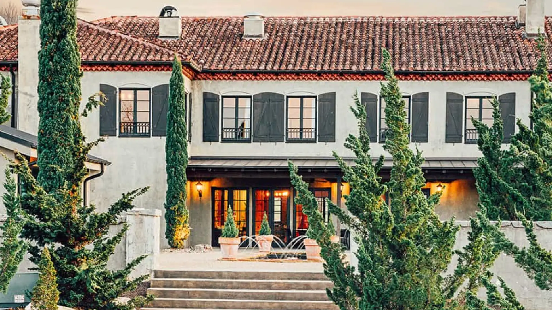 Hotel Domestique with cypress trees and a fountain at dusk