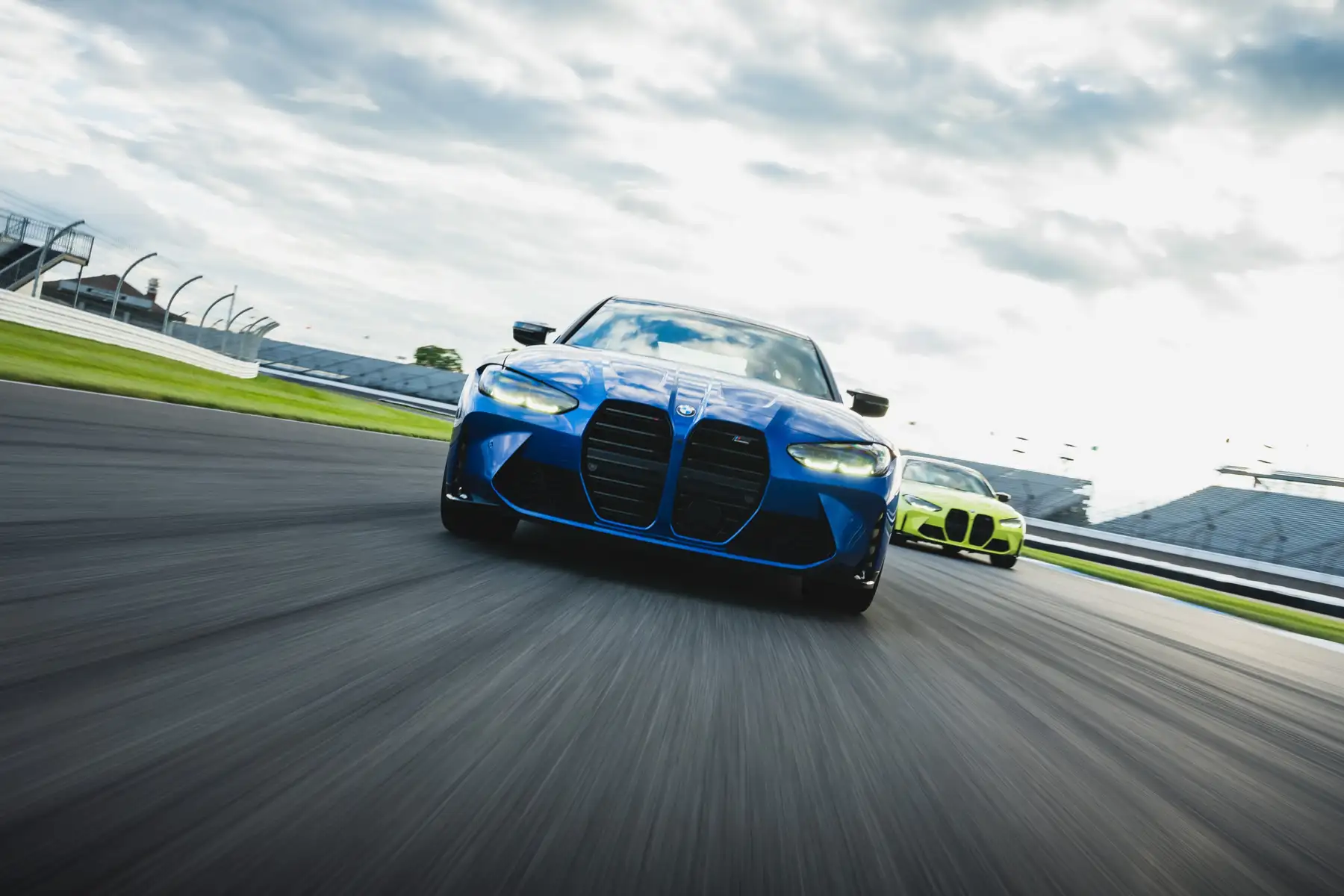 Blue BMW M4 leading a lime green M4 at Indianapolis Motor Speedway