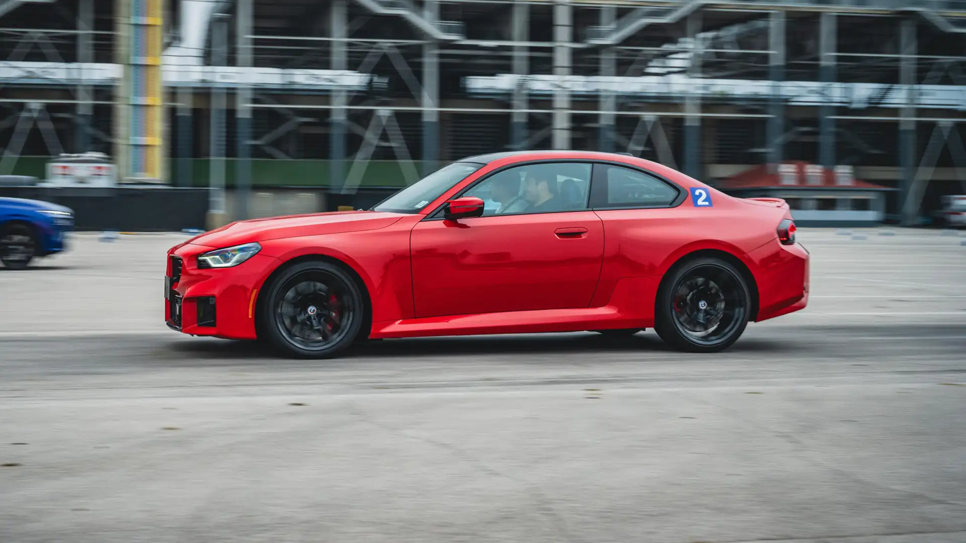 Red BMW M2 at speed past the grandstands at Indianapolis