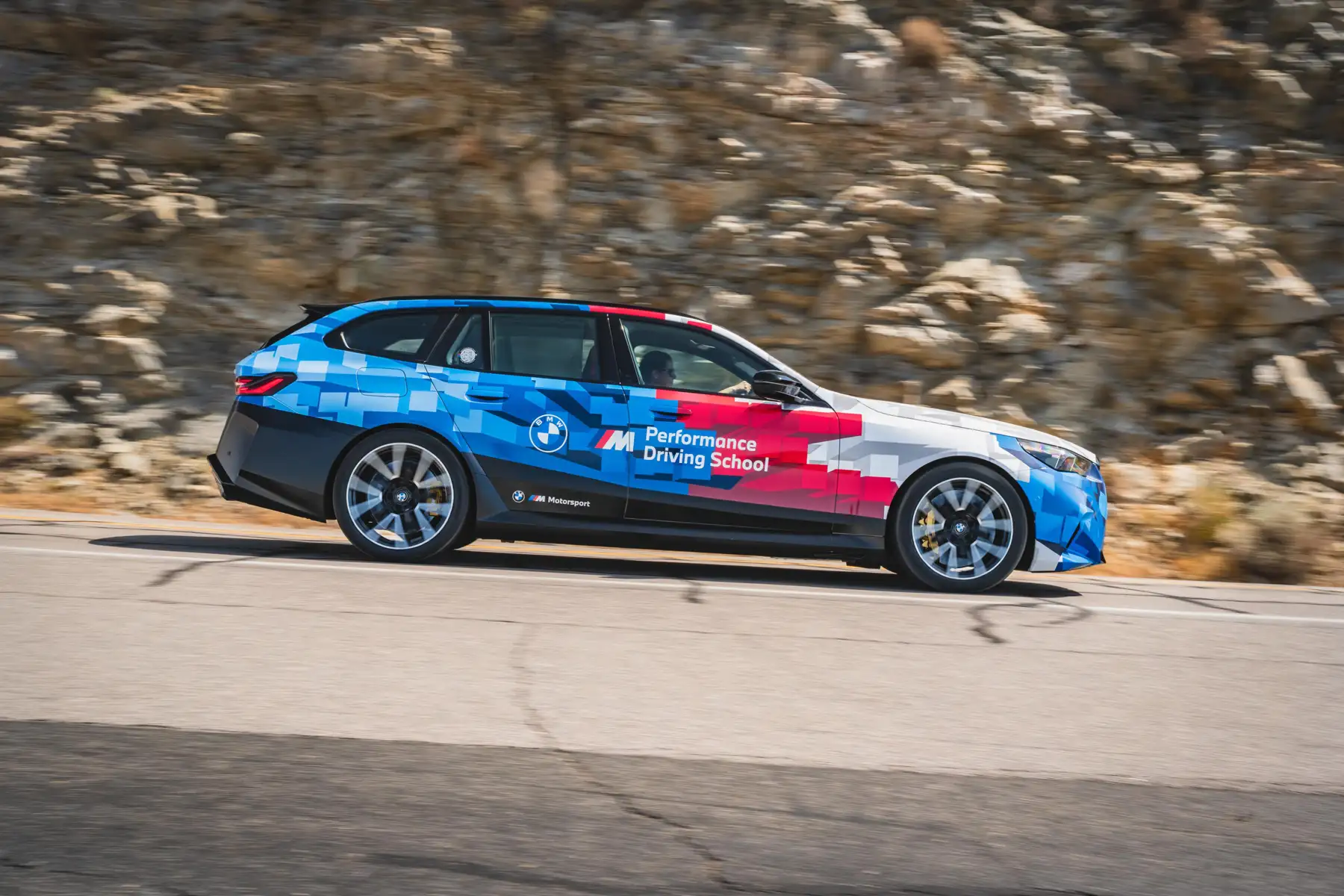 BMW M5 Touring in Motorsport livery on a rocky mountain road