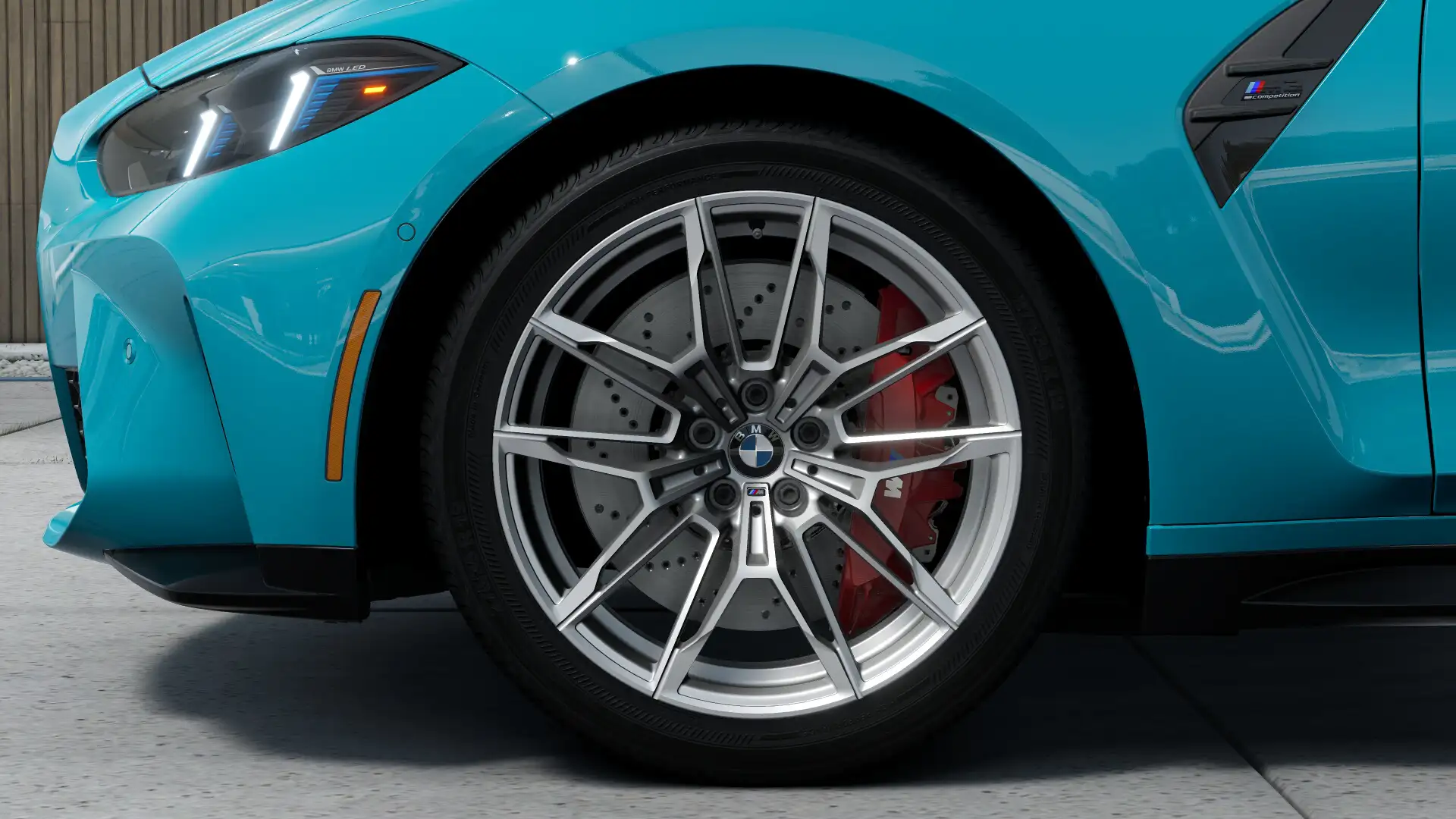 Close-up of a Miami Blue BMW M3's wheel and red brake caliper
