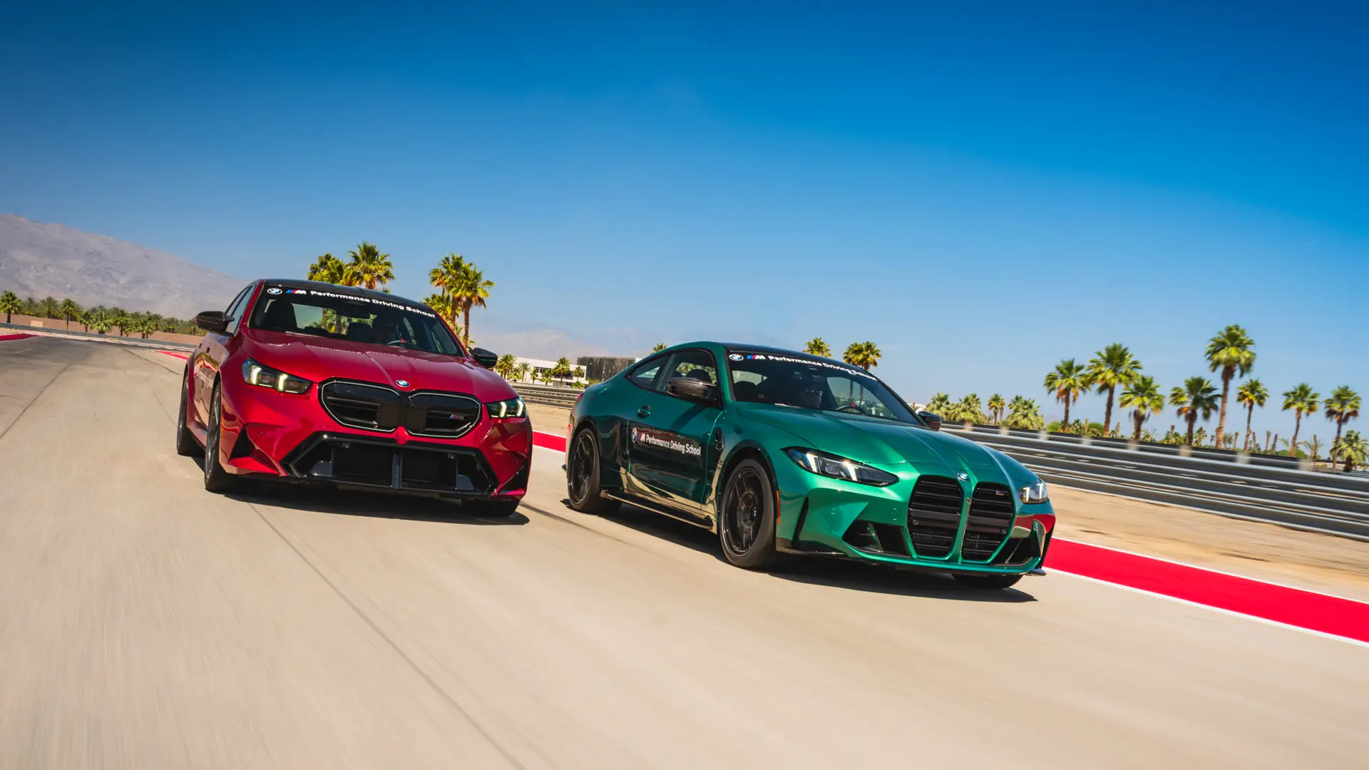 Red BMW M5 alongside a green M4 on the desert circuit