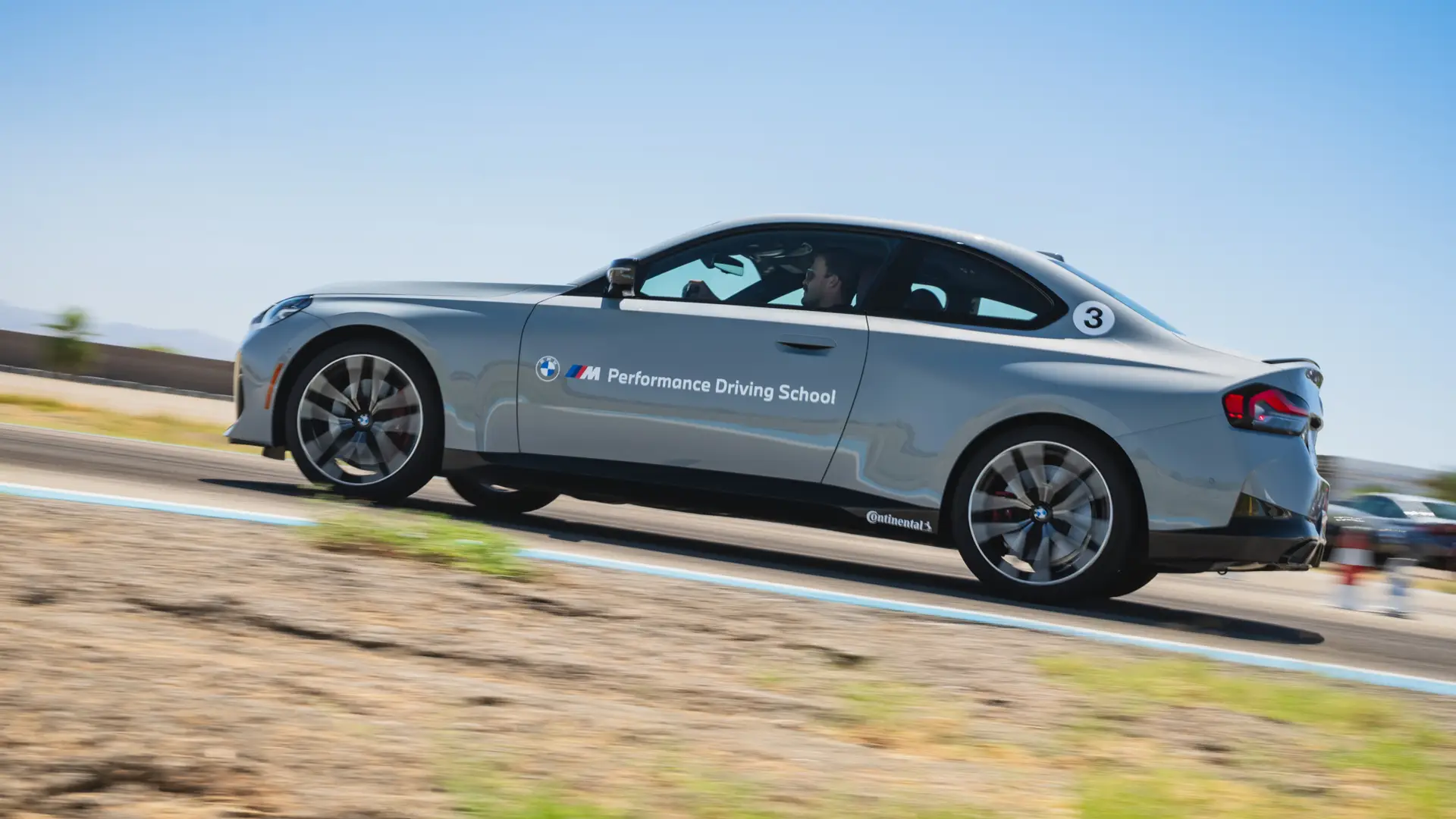 Grey BMW M2 at speed alongside the circuit