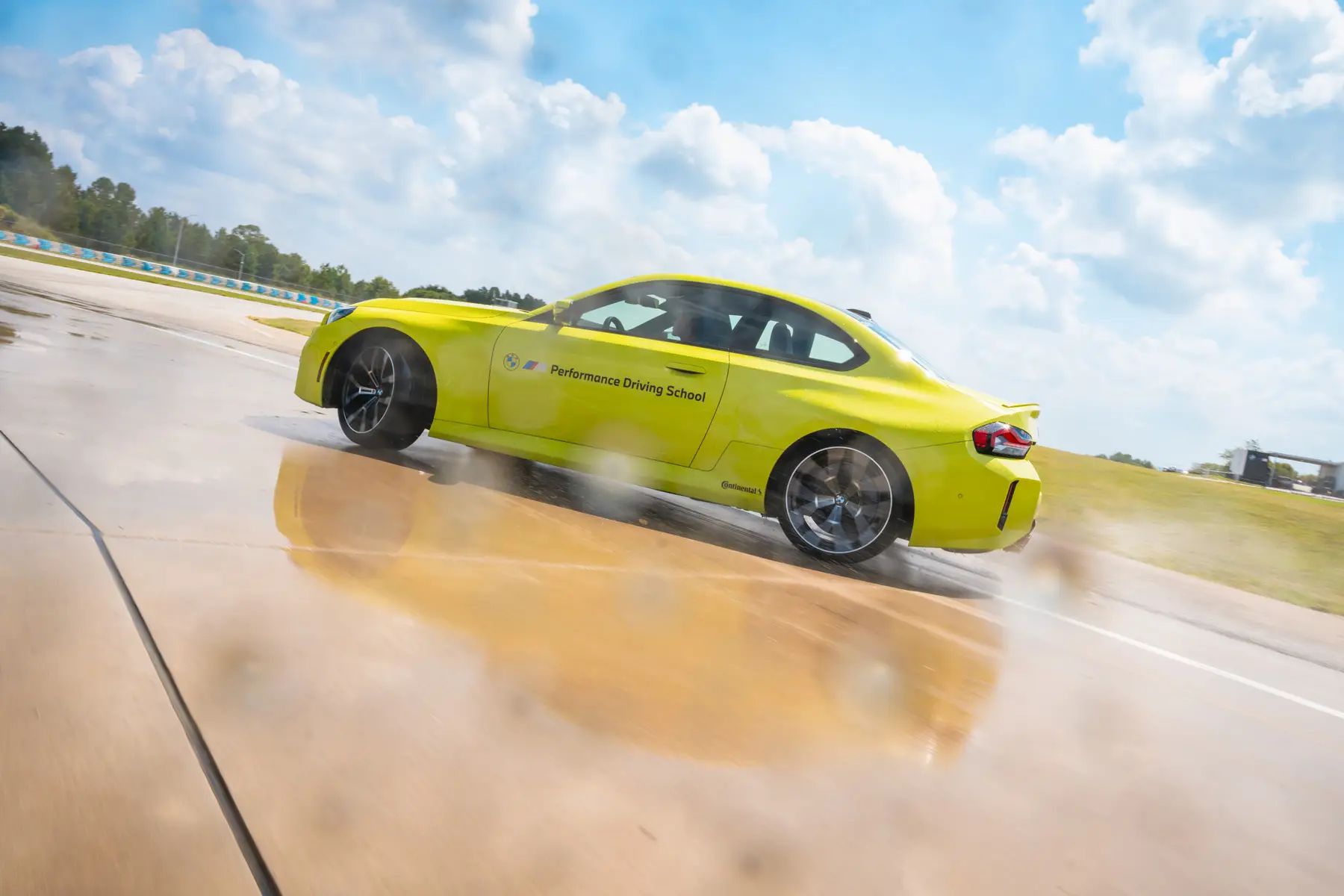 Lime green BMW M2 sliding across the polished wet skid pad