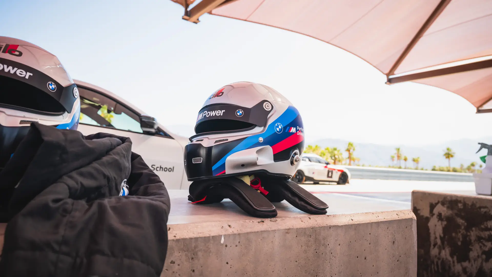 BMW M Power helmet and gloves resting on a wall beside the track