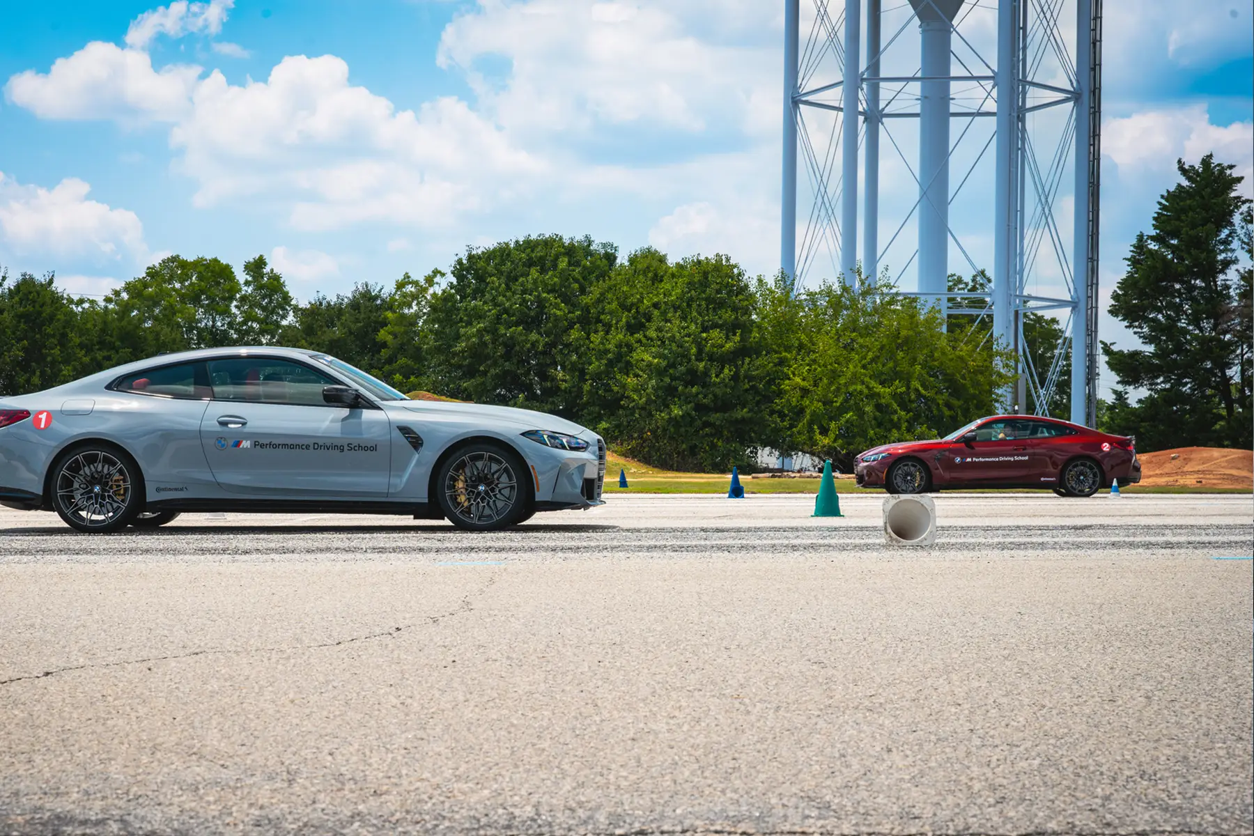 Grey and dark red BMW M4s on the exercise pad beneath the water tower