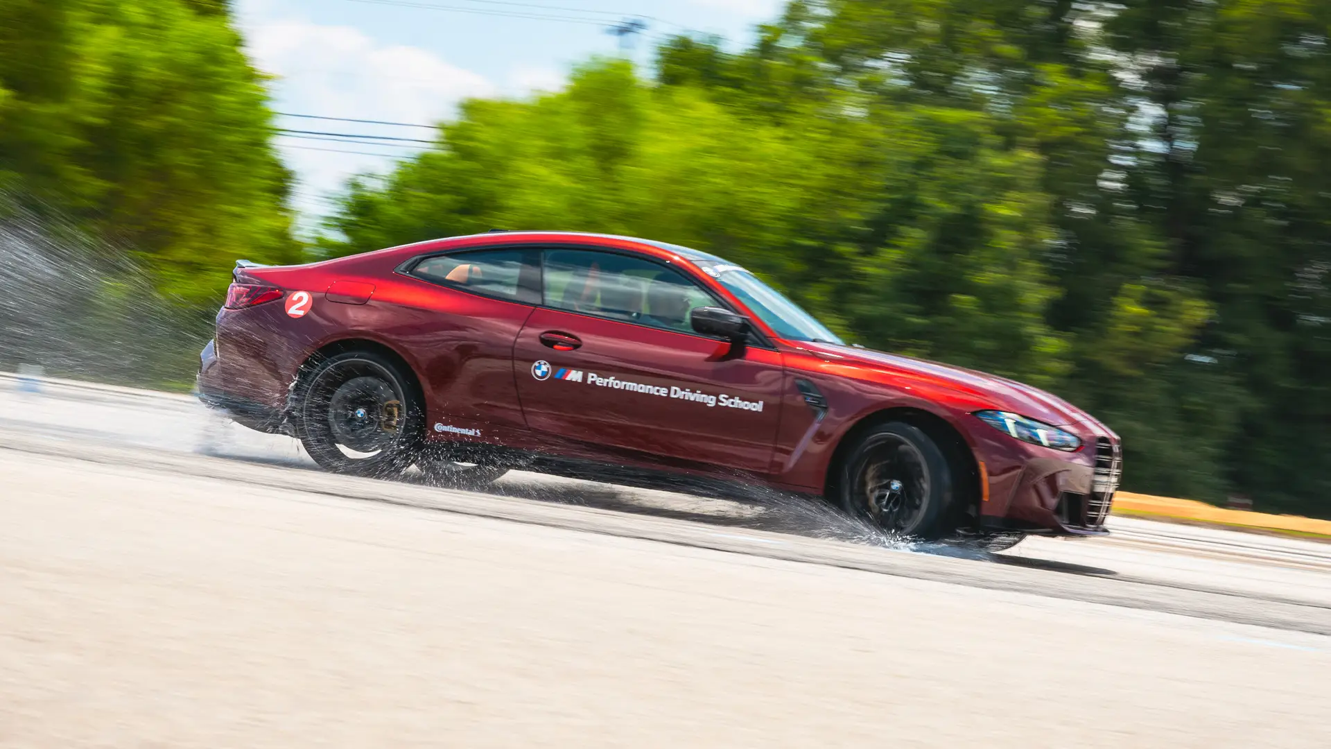 Dark red BMW M4 sliding through standing water