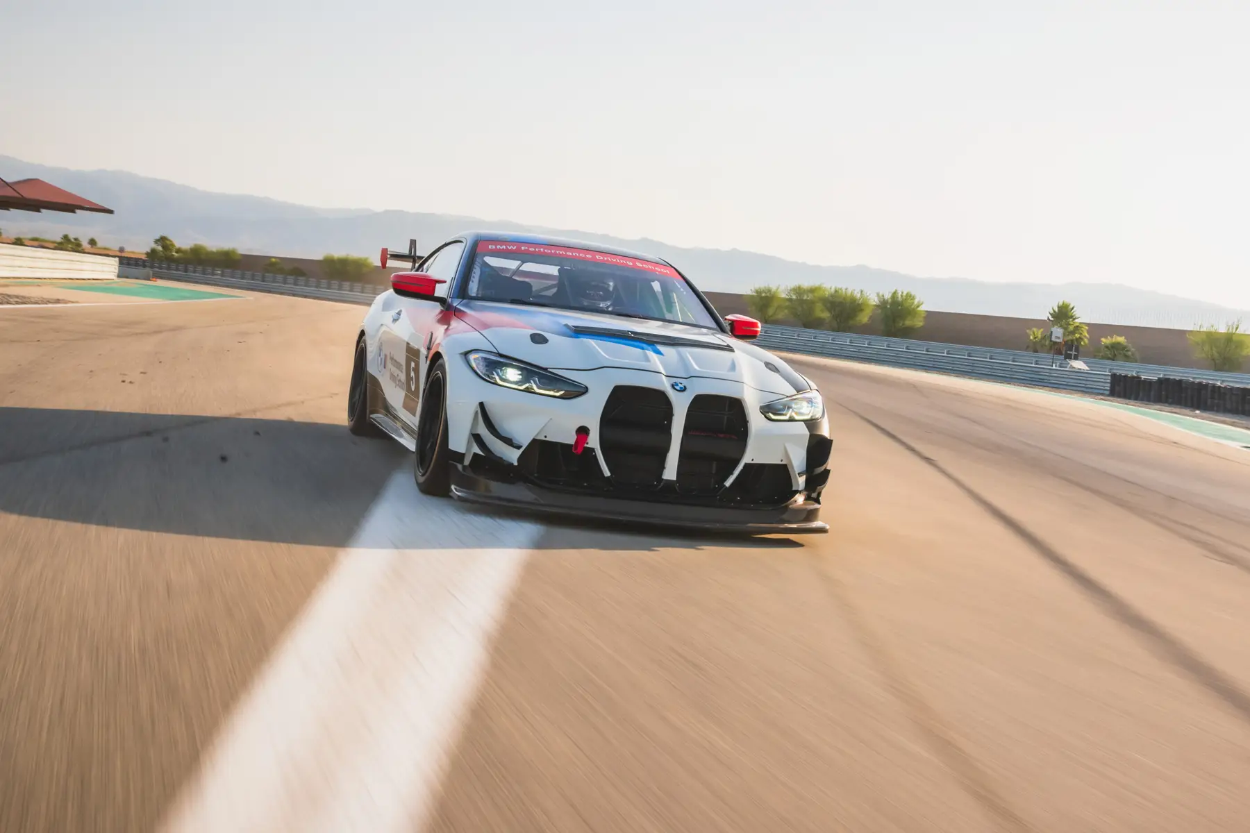 BMW M4 GT4 race car at speed on the desert circuit