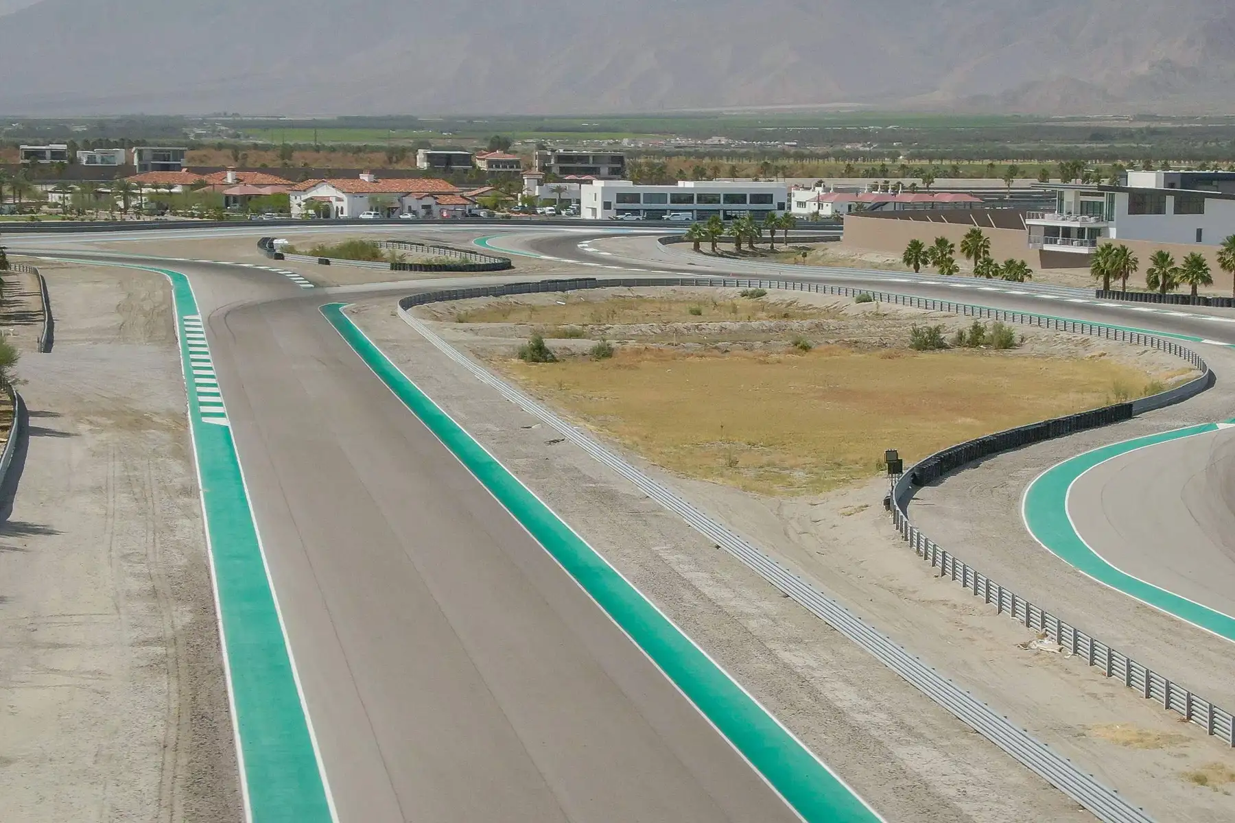 Green-kerbed corners of the desert circuit at The Thermal Club with villas beyond
