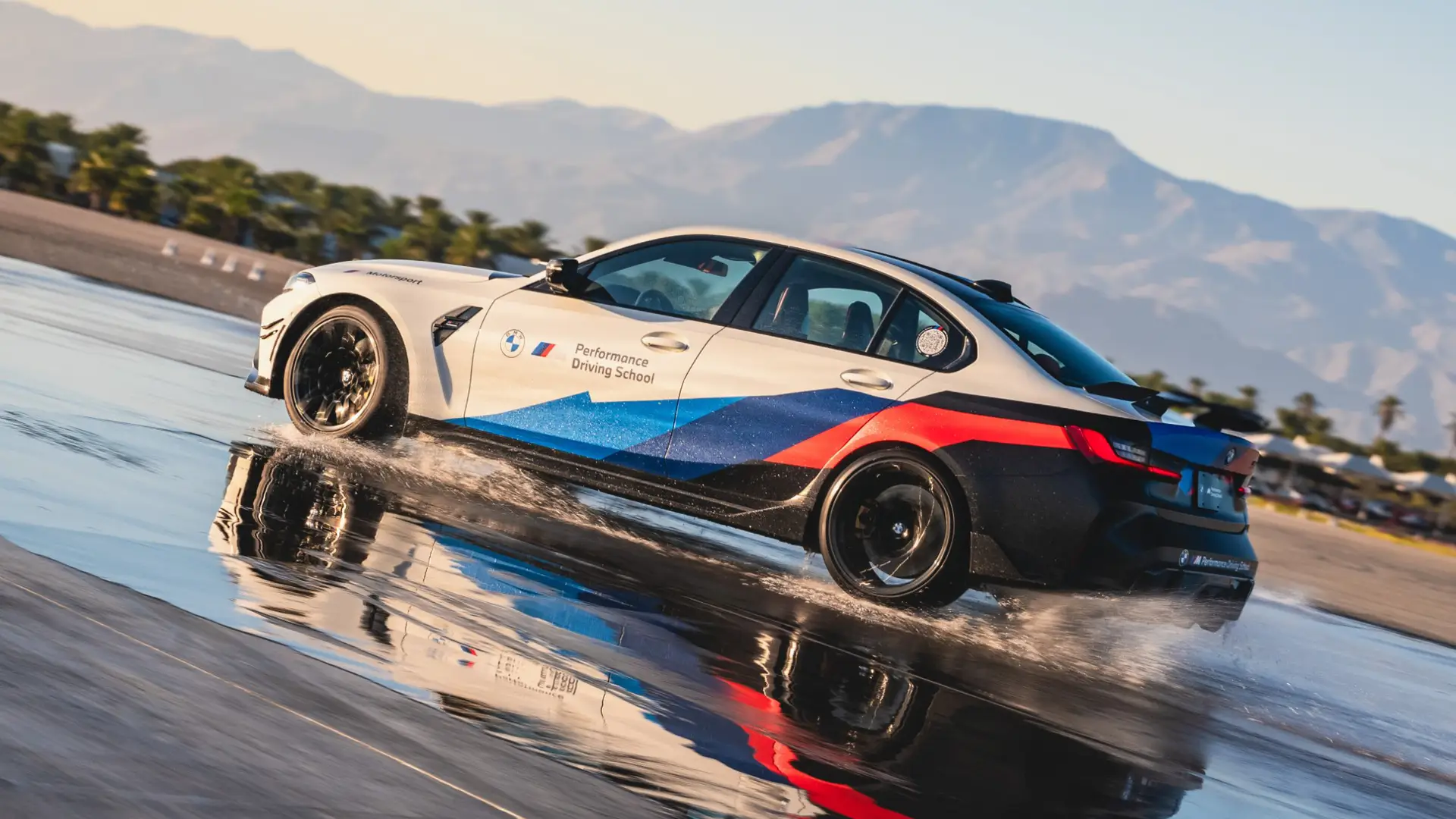 White BMW M3 in Motorsport livery sliding through standing water