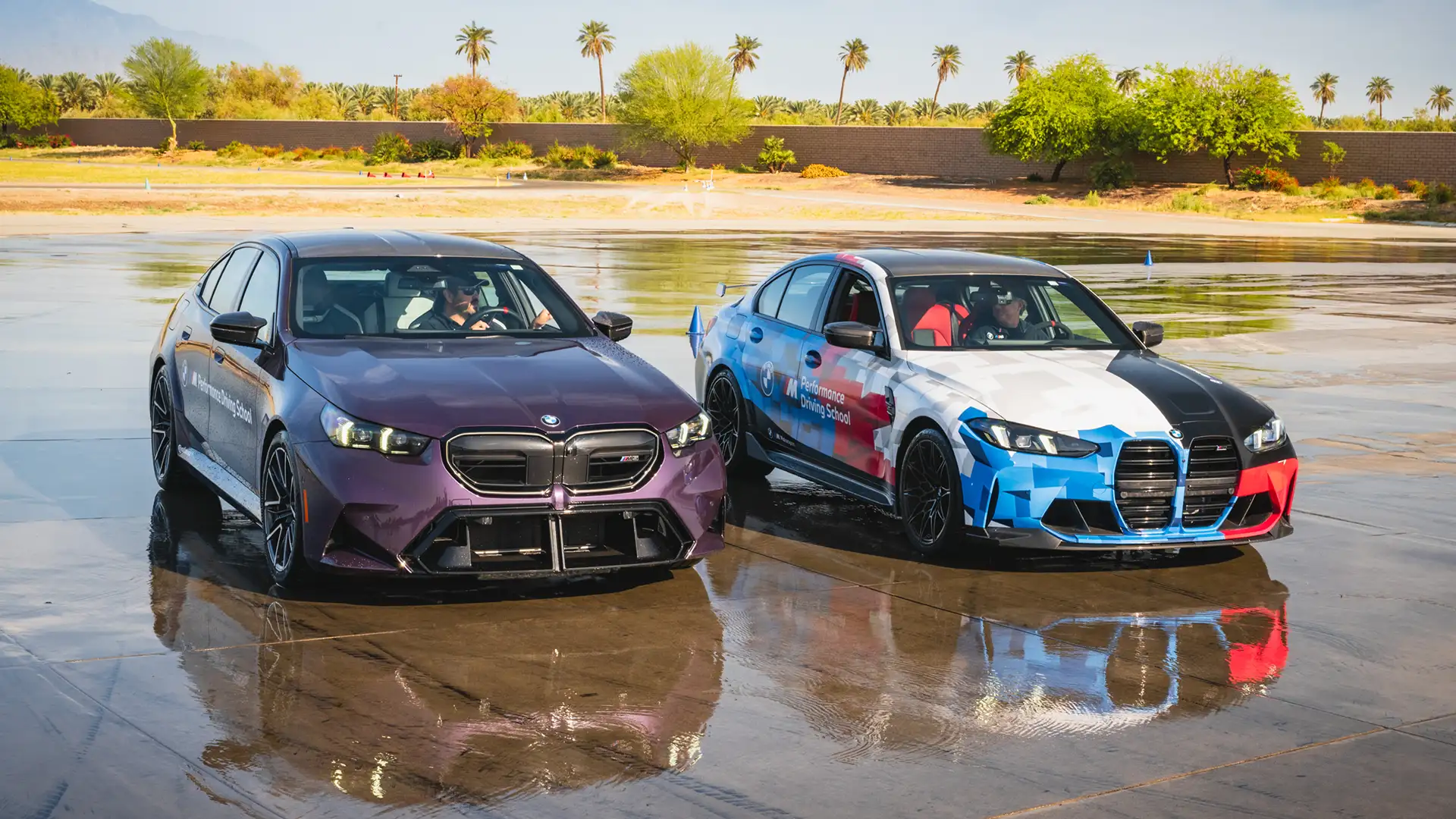 Purple BMW M5 and a liveried BMW M3 side by side on the wet skid pad