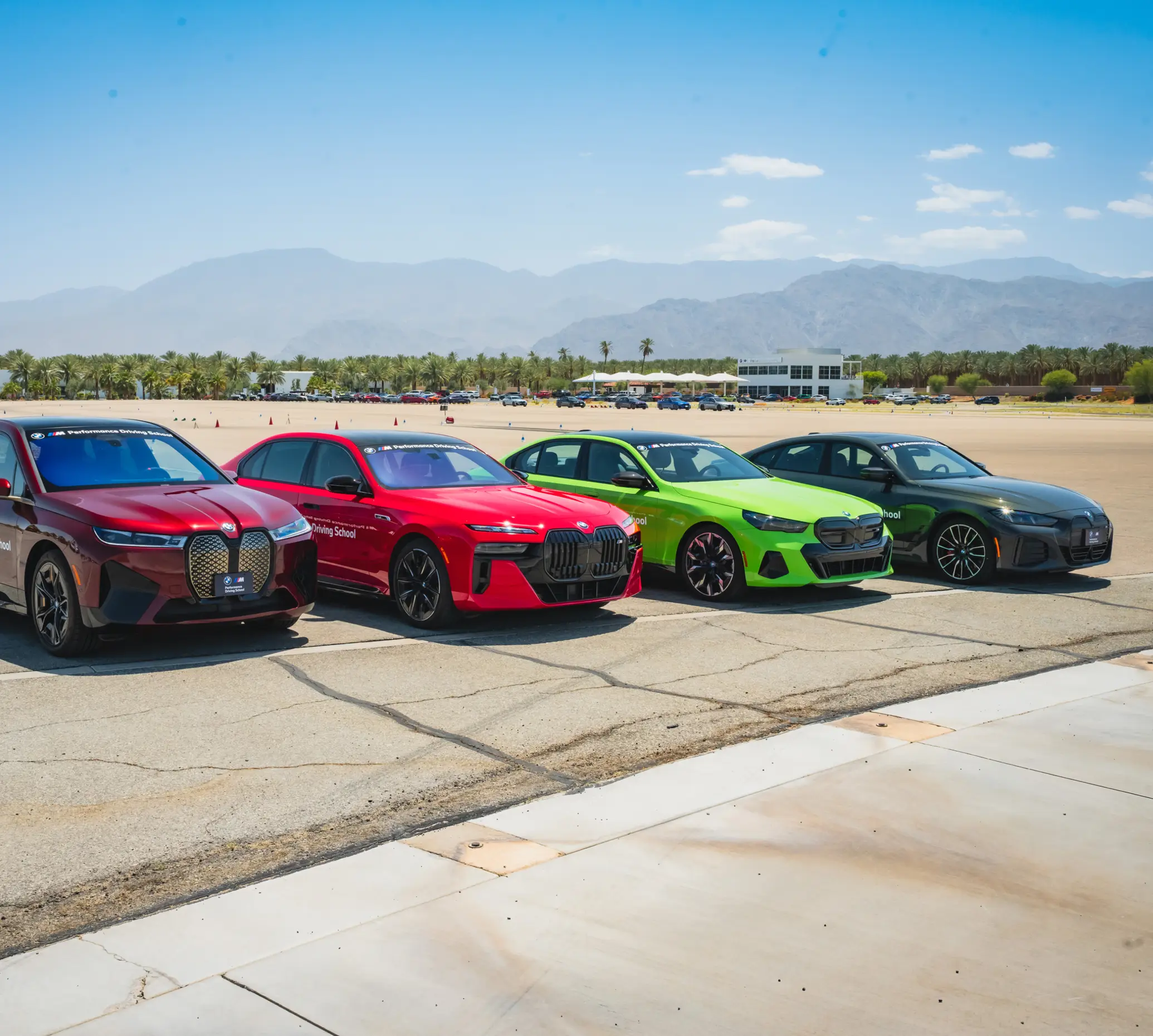 Four BMW electric cars lined up in the desert, including a bright green i5