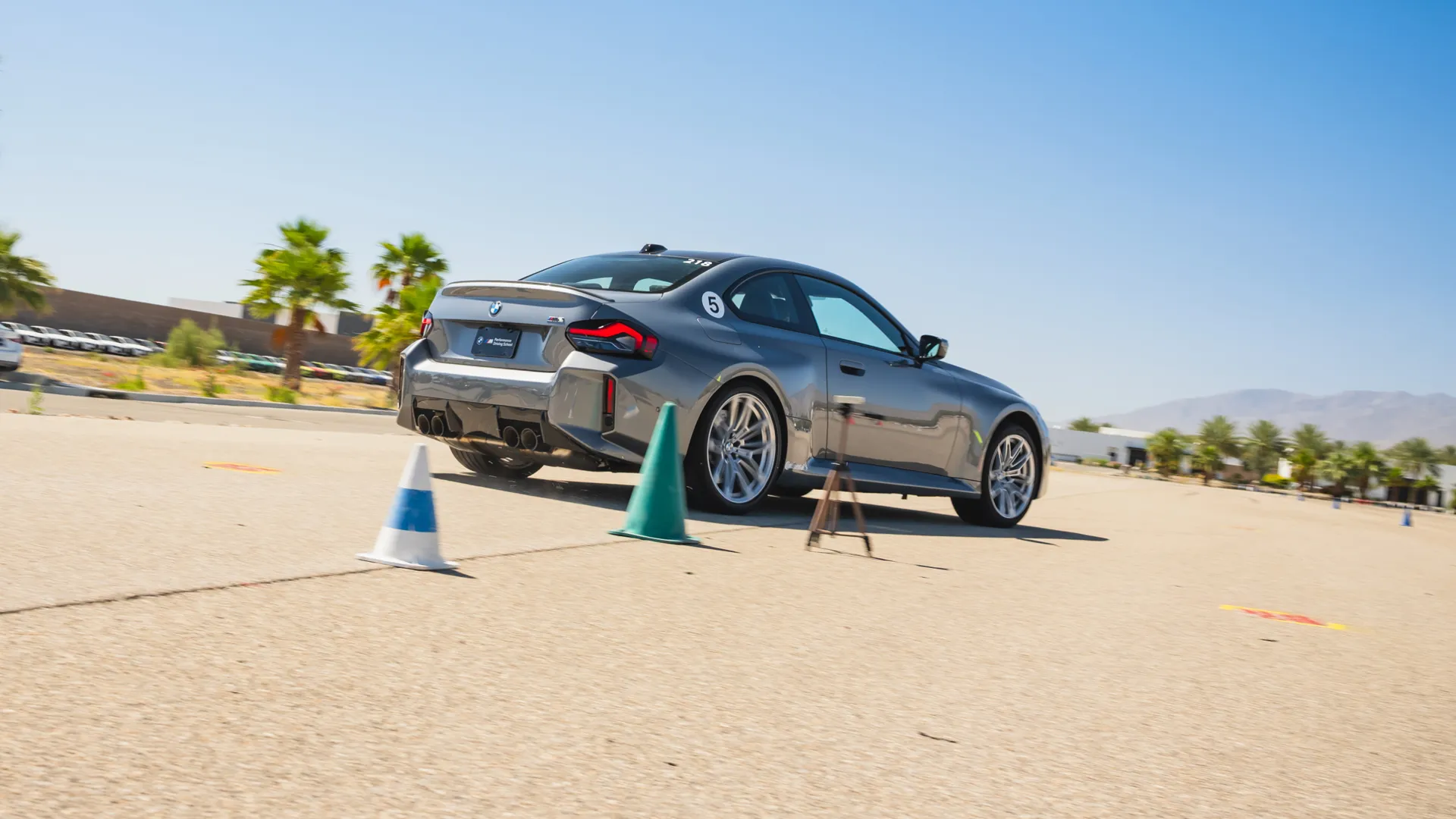 Grey BMW M2 on a coned course beside a timing tripod
