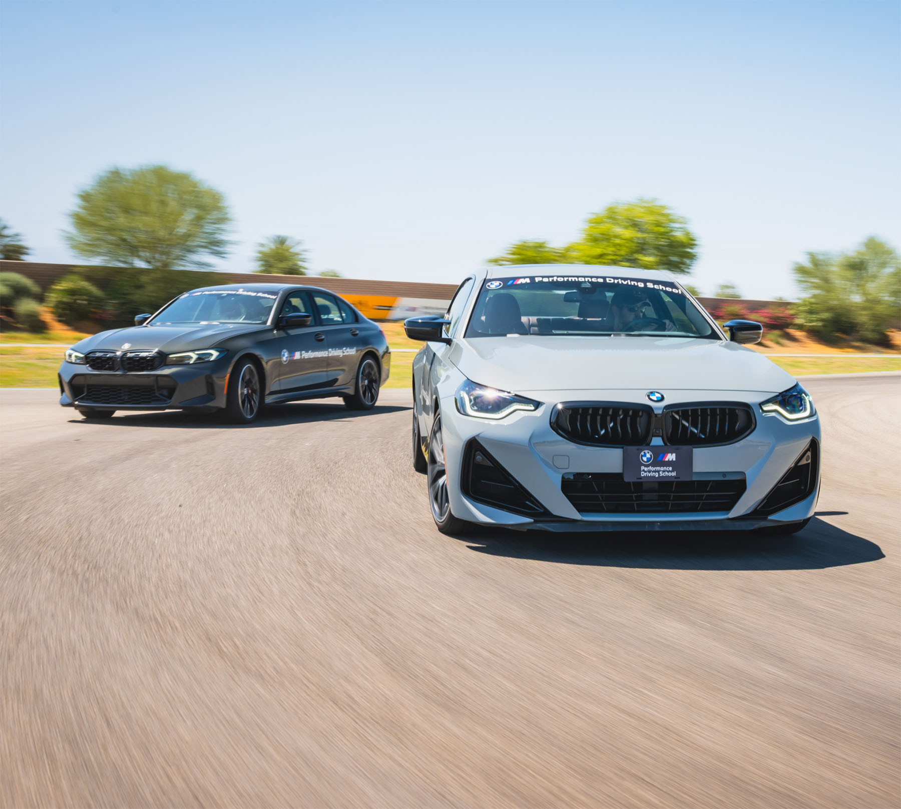 White BMW M2 leading a dark BMW M3 through a corner