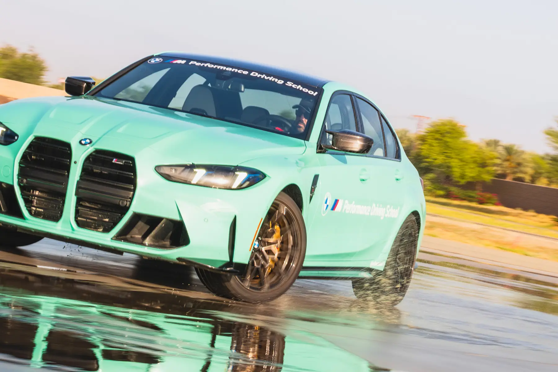 Mint green BMW M3 sliding across the wet skid pad