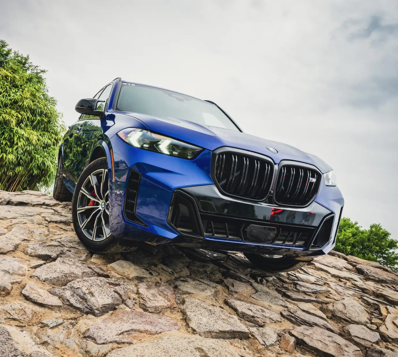 Blue BMW X5 M60 posed on a rocky outcrop