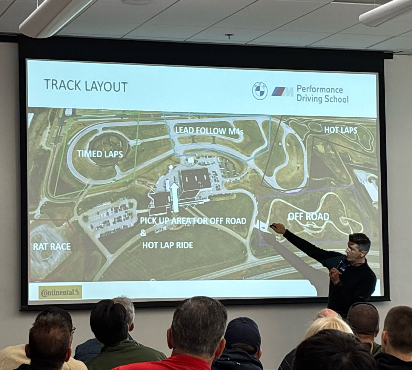Instructor pointing to a labelled track layout slide during a classroom briefing