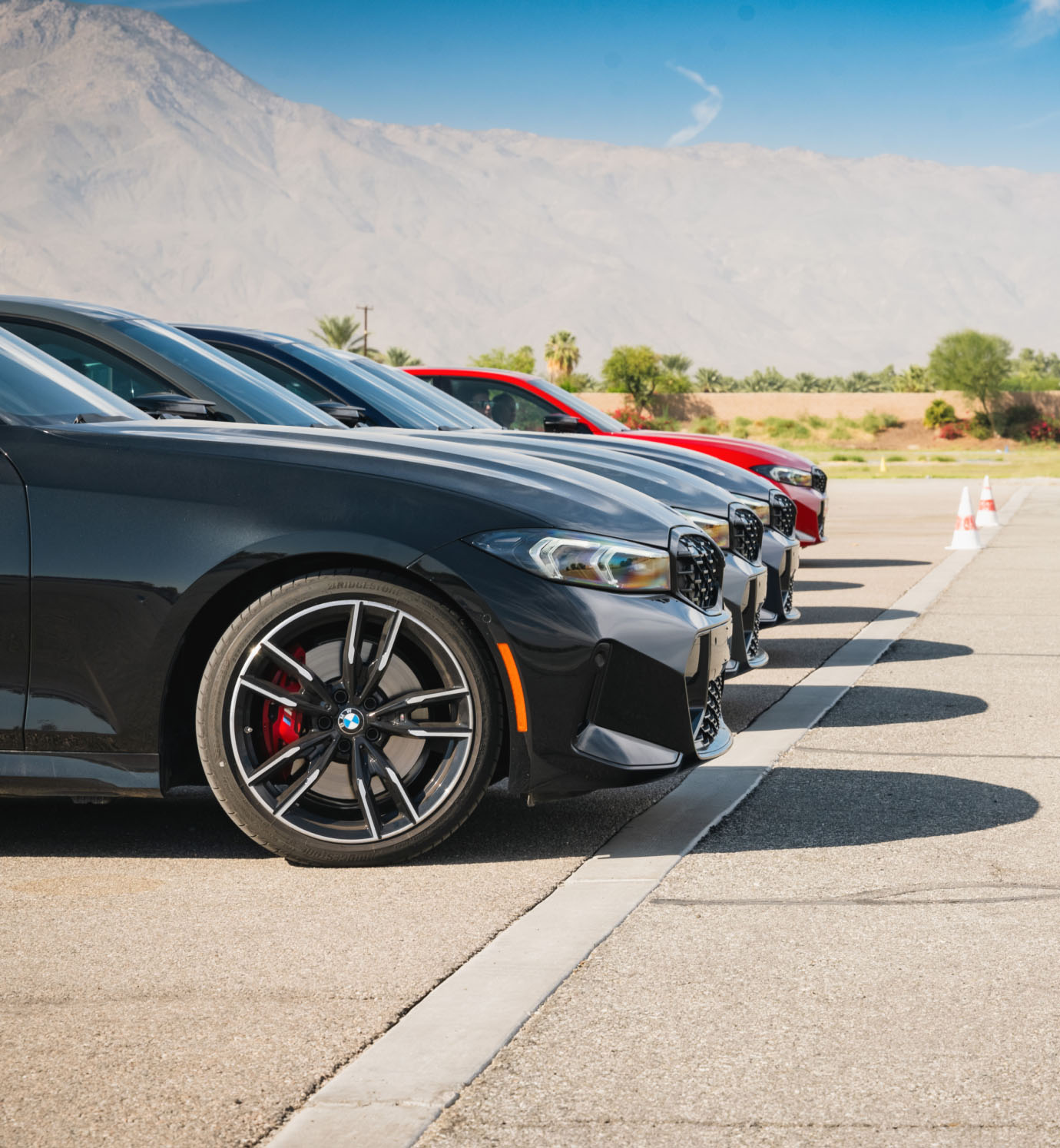 Row of BMW M340is parked in the desert with mountains behind
