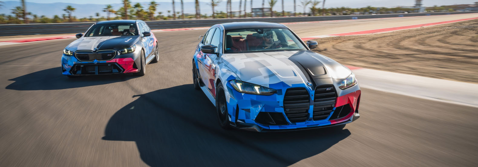 BMW M3 and M5 in Motorsport livery running side by side on the desert circuit